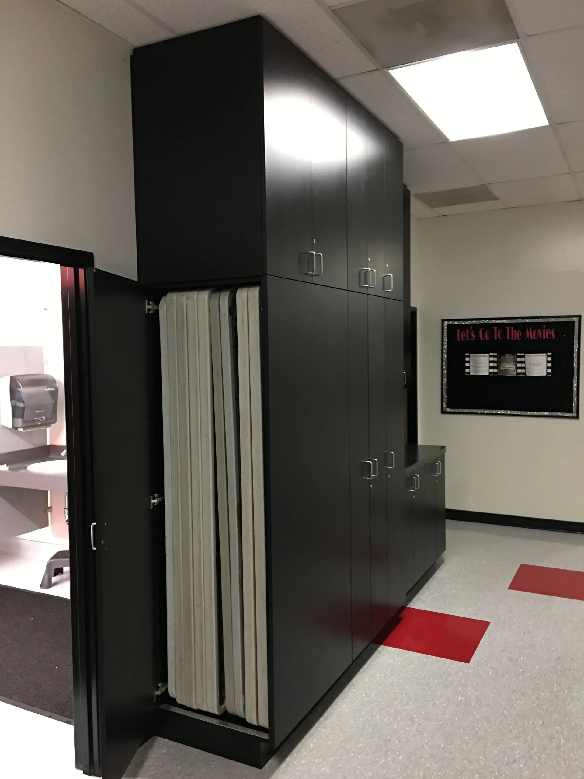 Black storage cabinet with hanging files in a fluorescent-lit office hallway