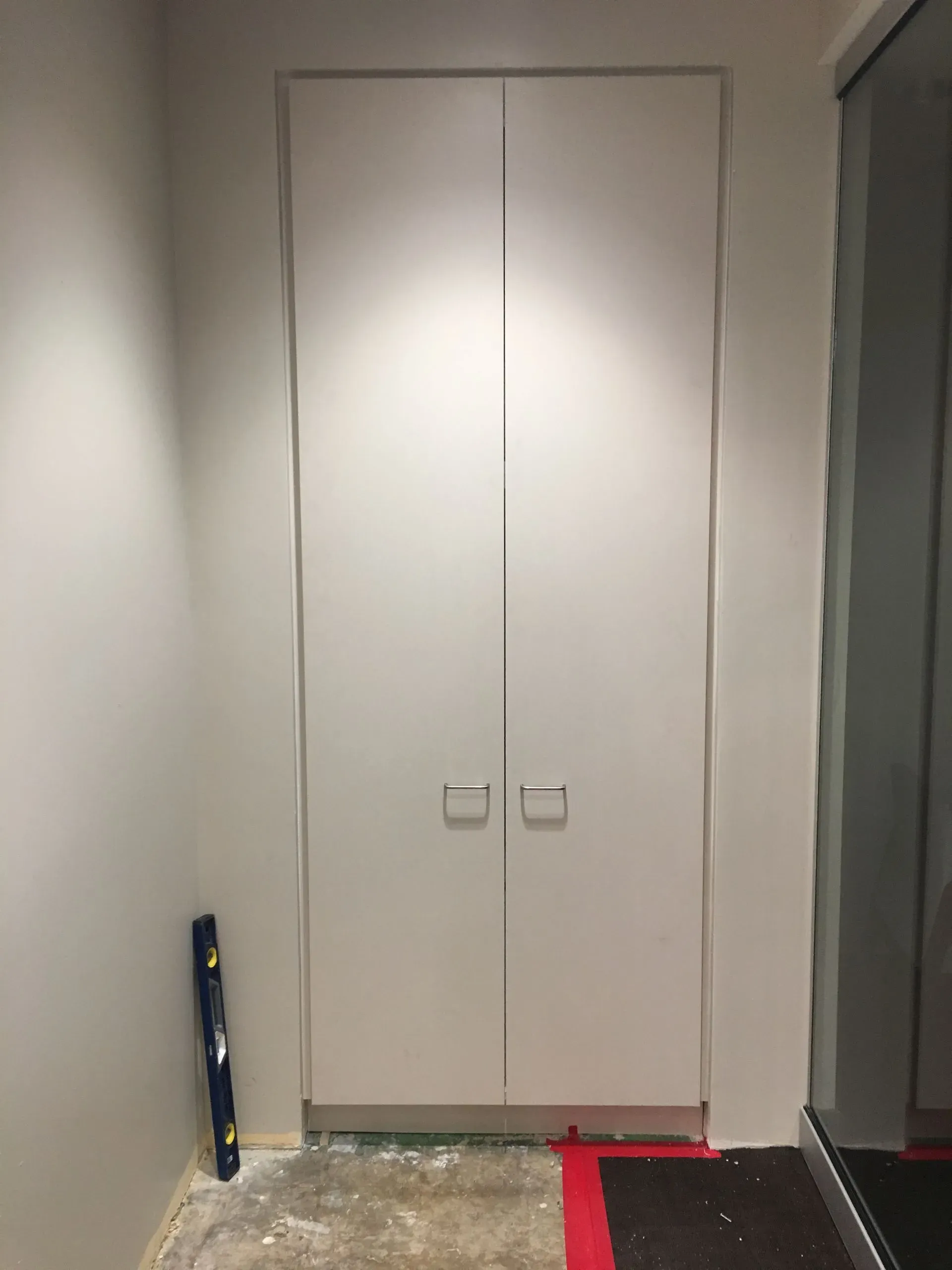Hallway closet with white double doors, partially blocked by a chair rail and a red floor mat.