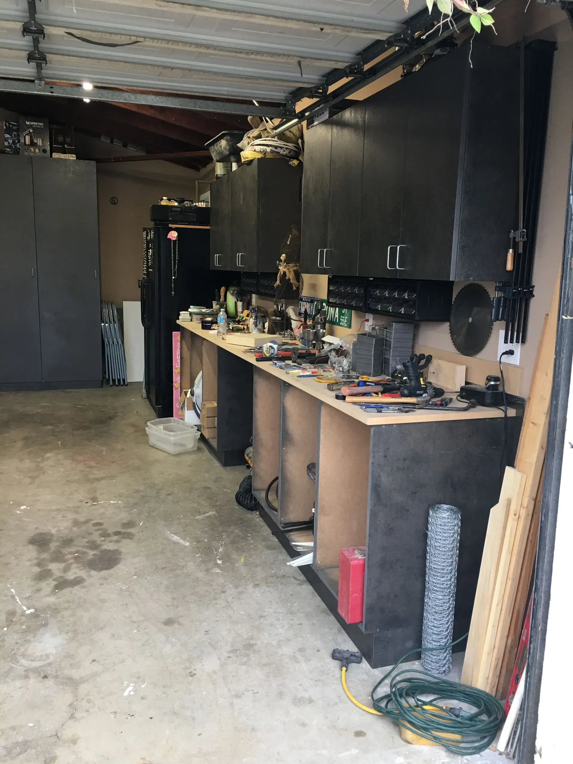 Garage workshop with workbench, cabinets, tools, and a concrete floor.