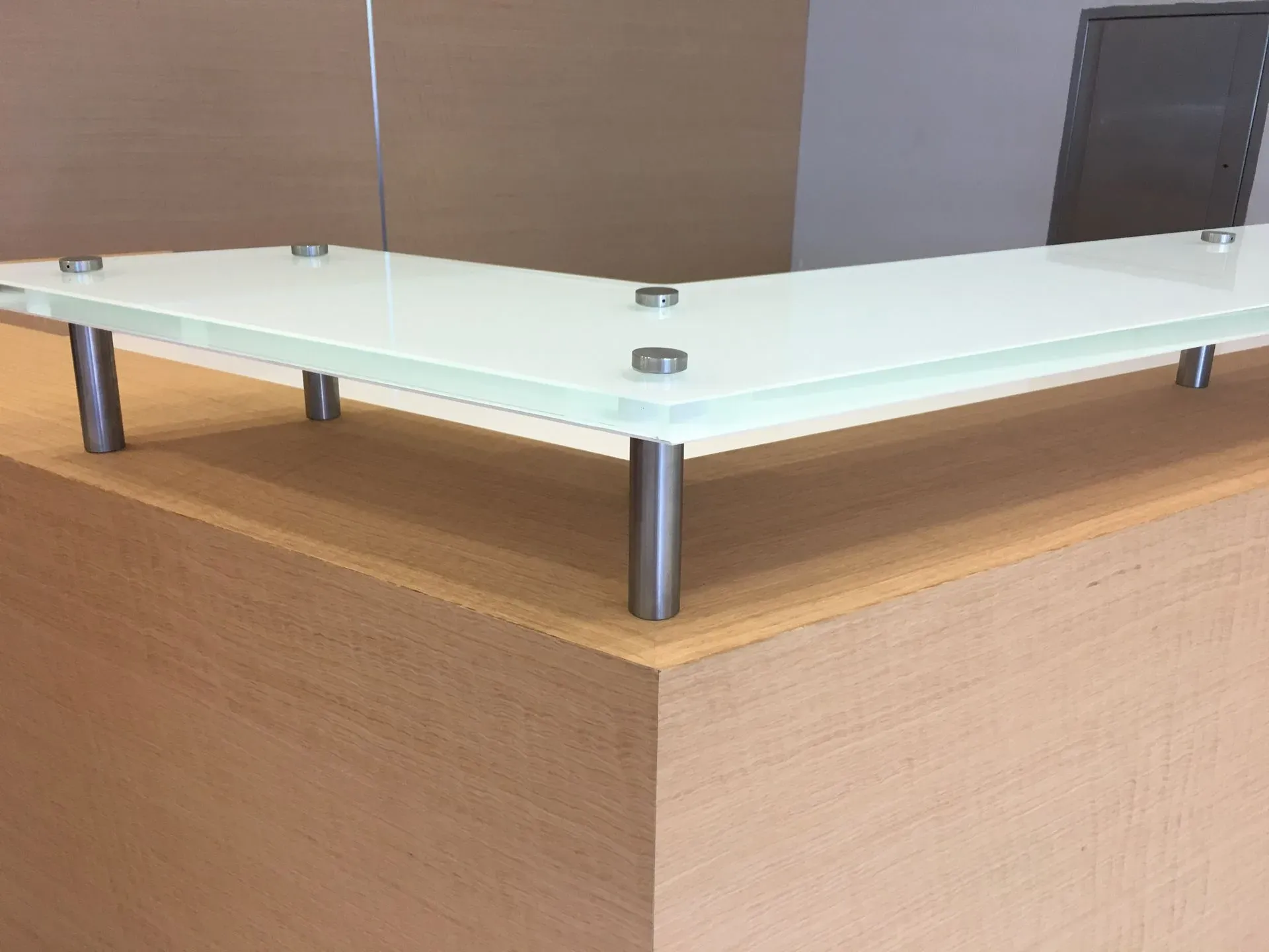 Glass display case on metal legs atop a wooden pedestal in a room