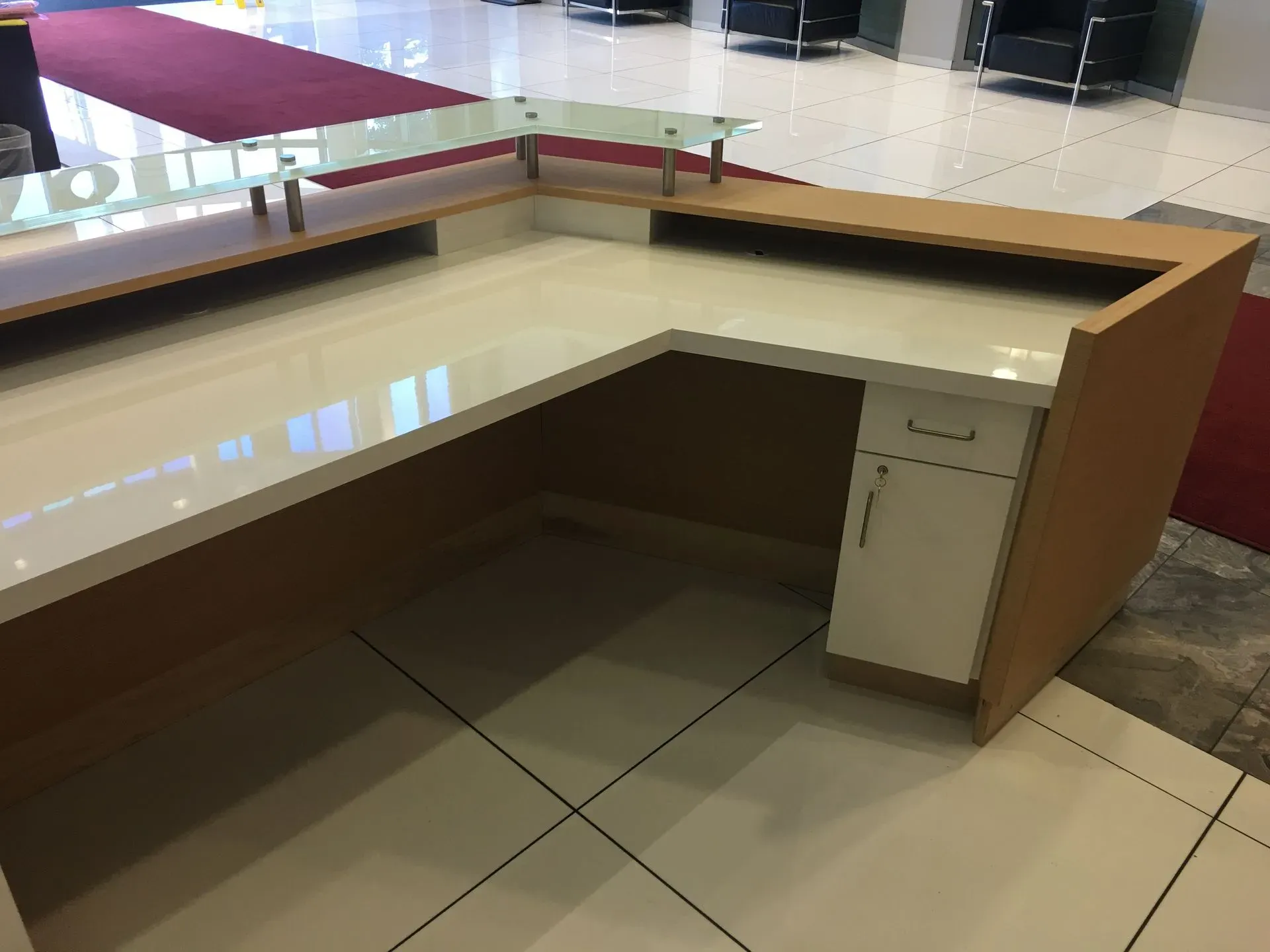 Empty wooden reception desk with beige tile floor in a lobby