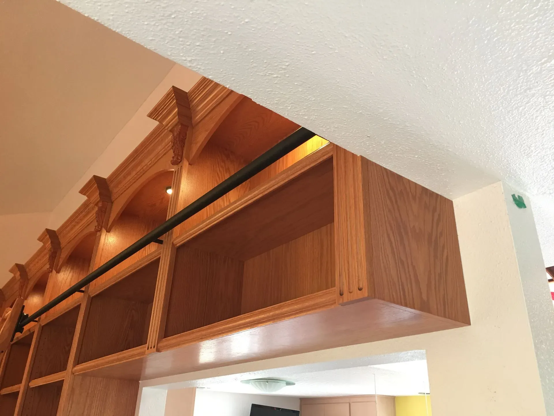 Wooden wall cabinets with open shelving and crown molding near a ceiling corner