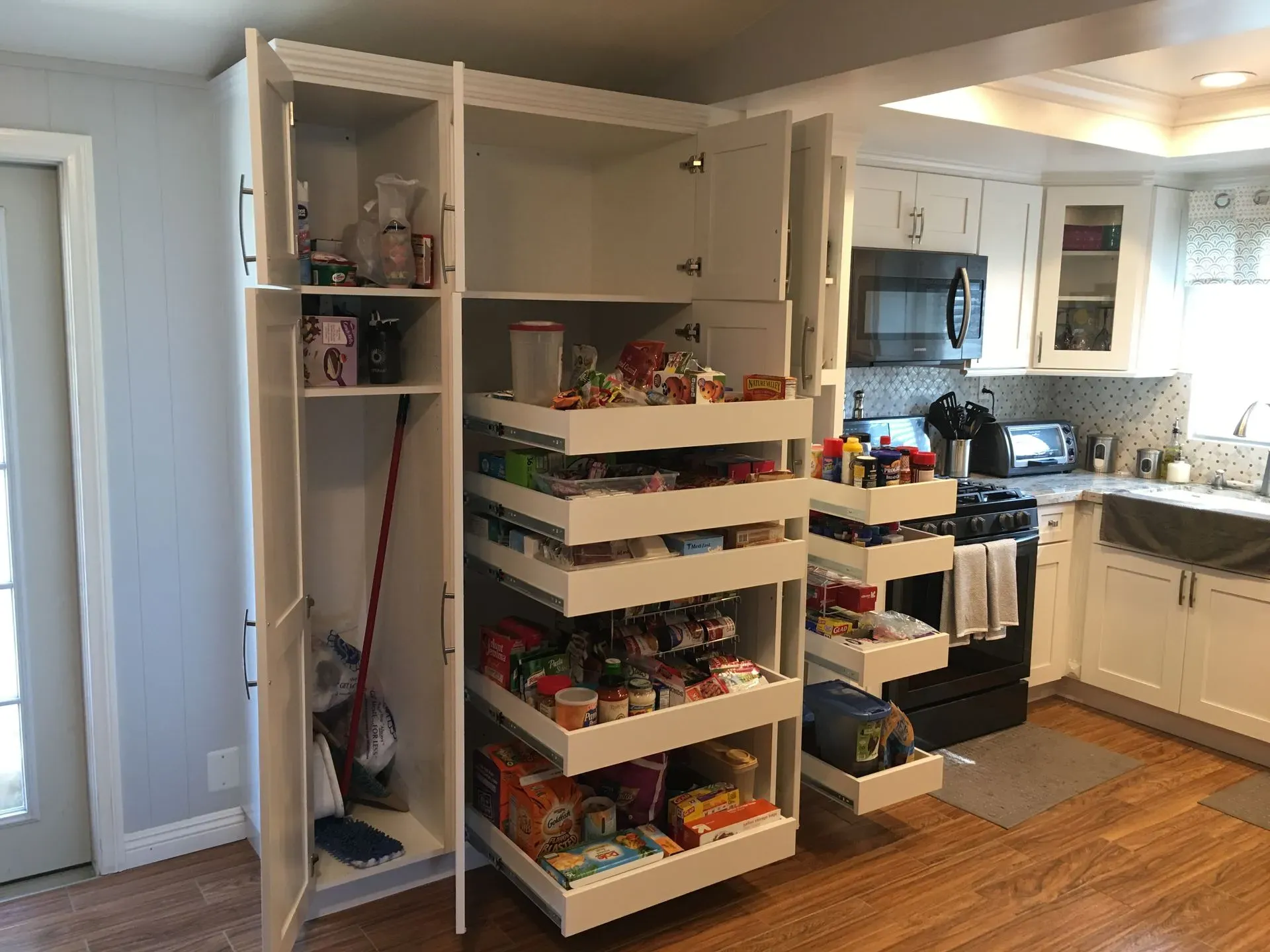 Kitchen with open pantry cabinet and pull-out shelves stocked with spices and groceries