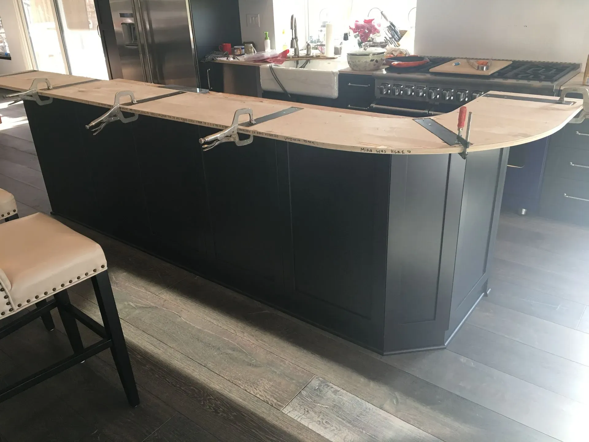 Curved black bar in a restaurant, with a rope barrier and chairs beside a dark wood floor.