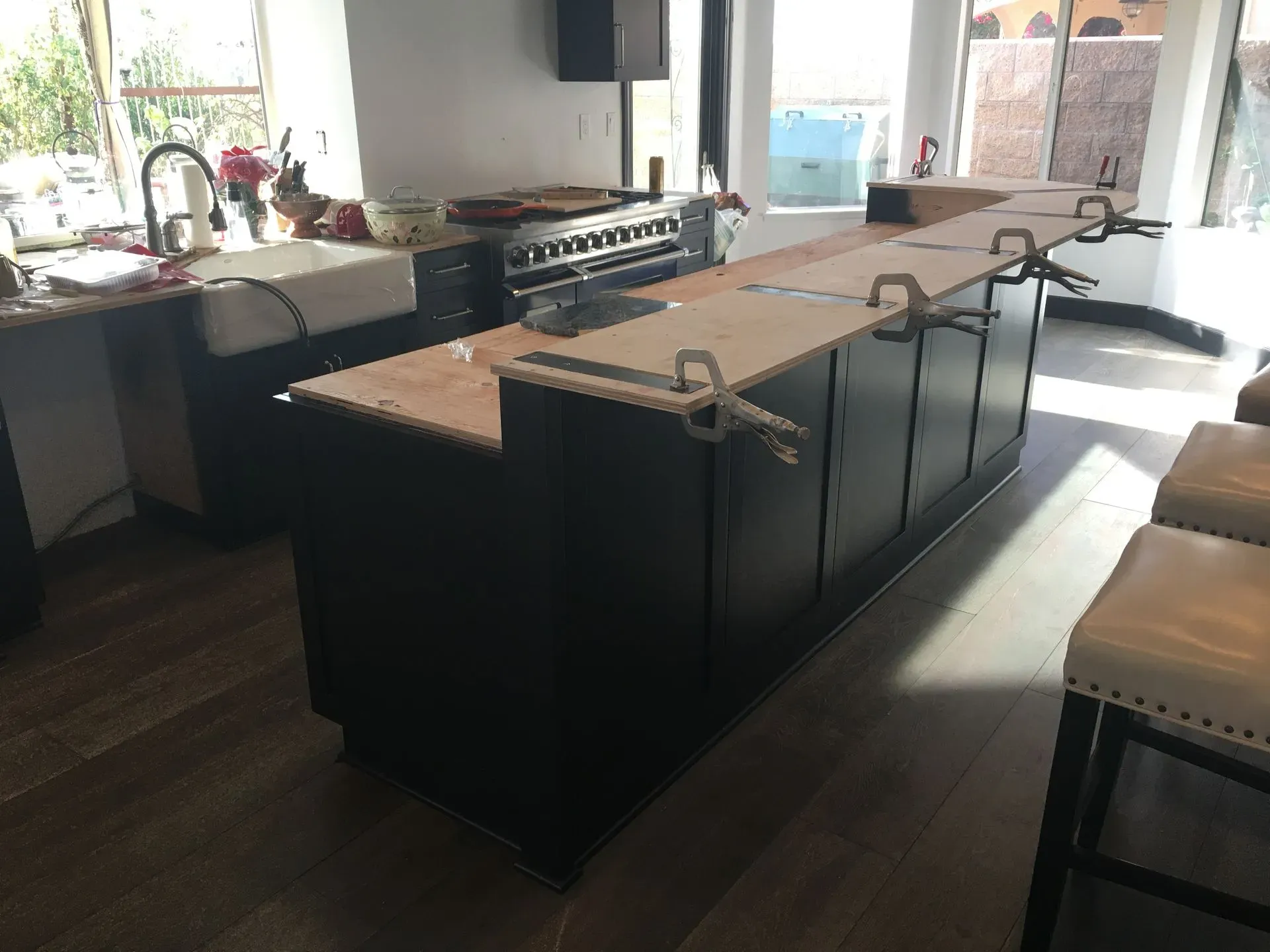 Modern kitchen with a large dark island, light countertops, and a stove by the window
