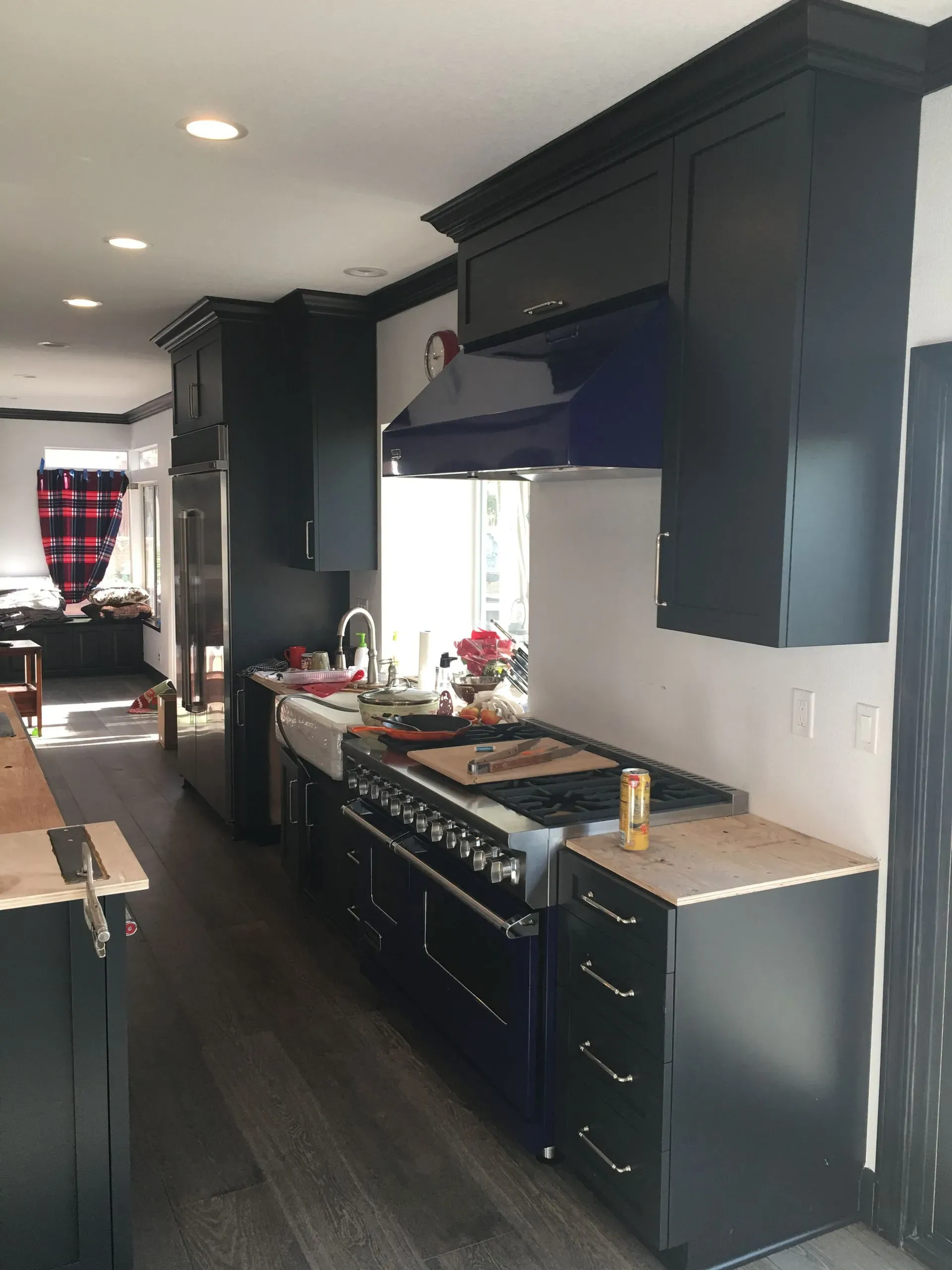 Modern kitchen with dark cabinets, gas stove, countertop decor, and a hallway view into another room