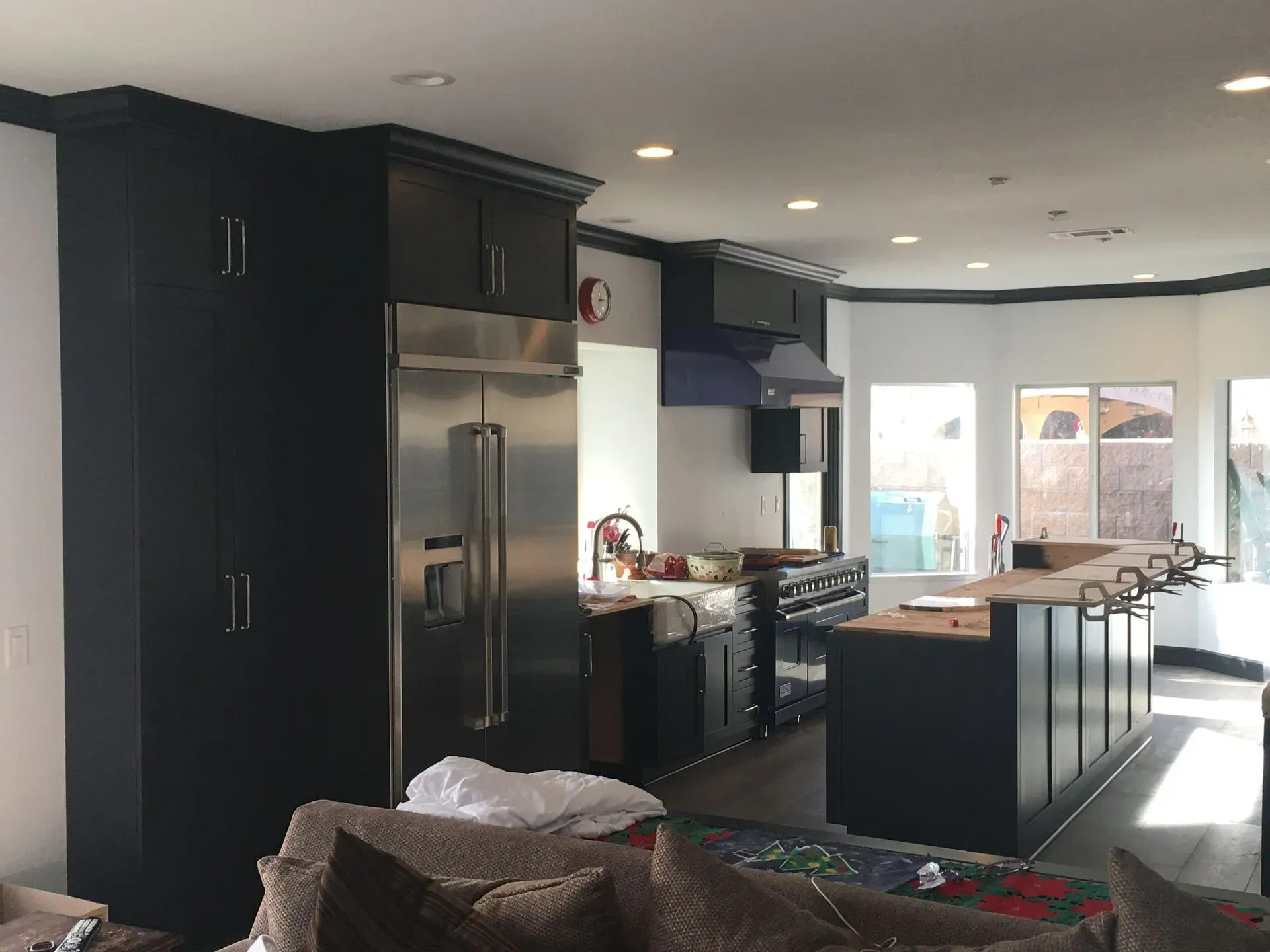 Modern kitchen with black cabinets, stainless steel appliances, island, and large windows