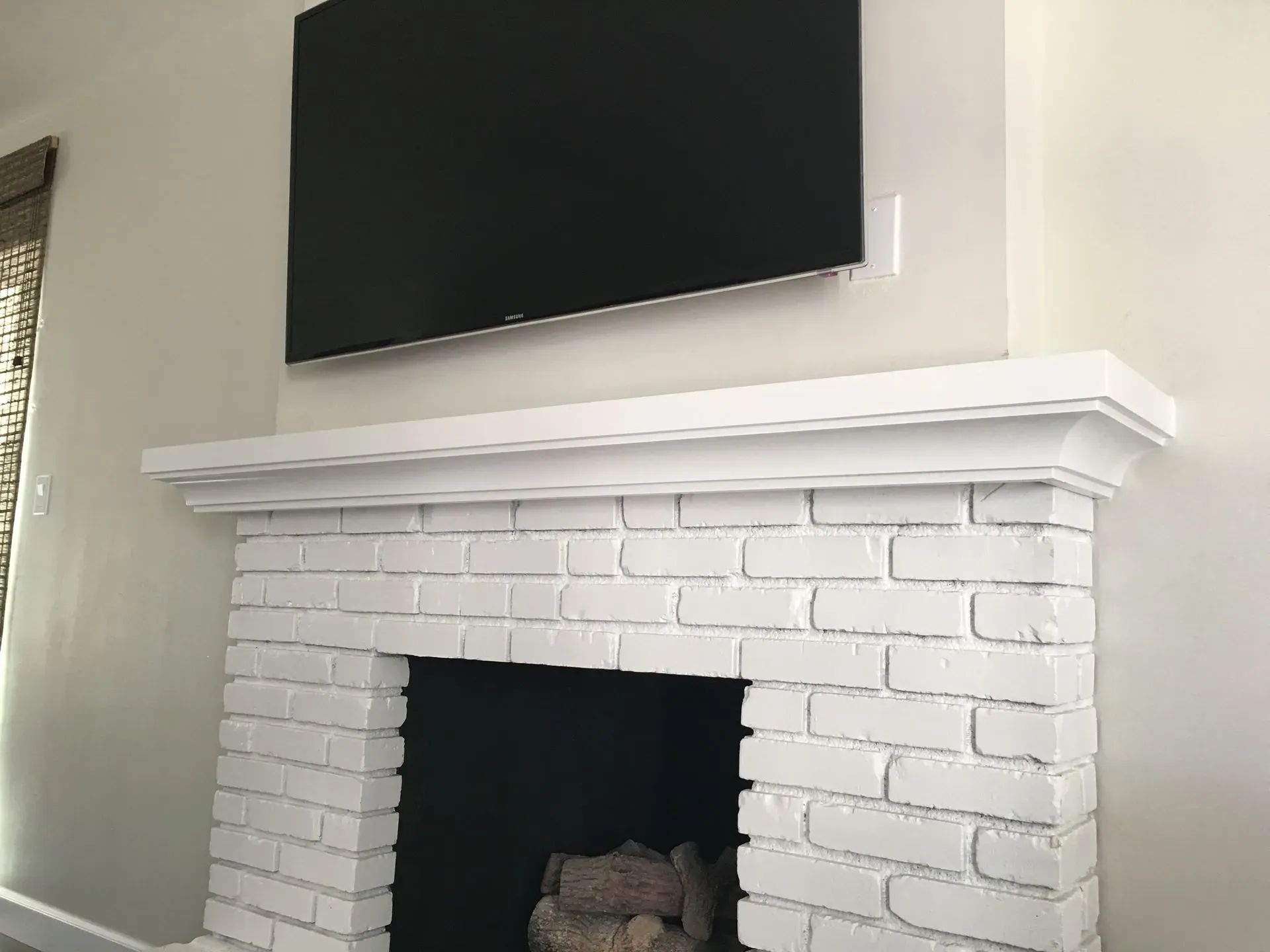 White brick fireplace with a TV mounted above it in a living room.