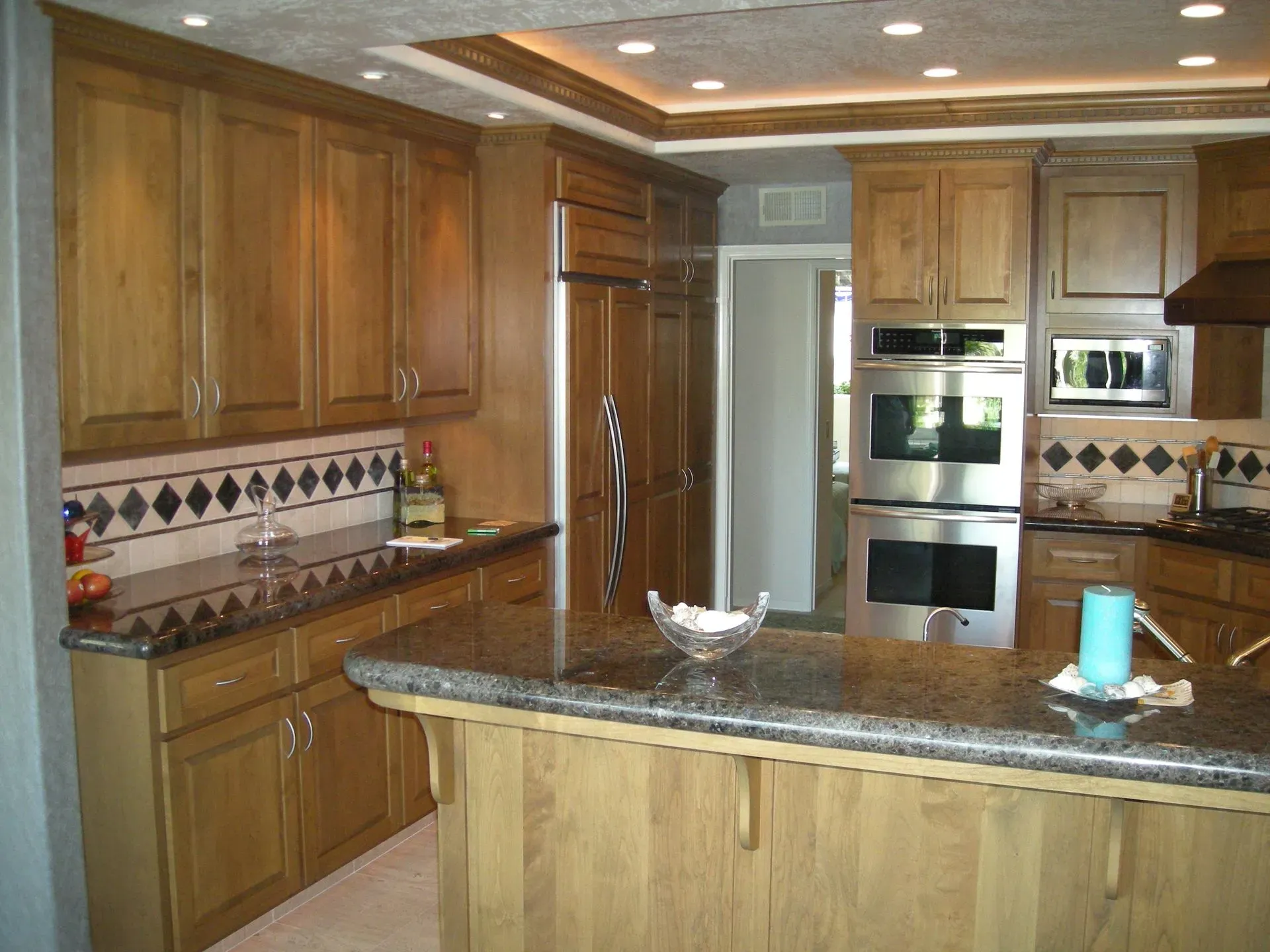 Modern kitchen with wood cabinets, granite island, stainless steel appliances, and tiled backsplash