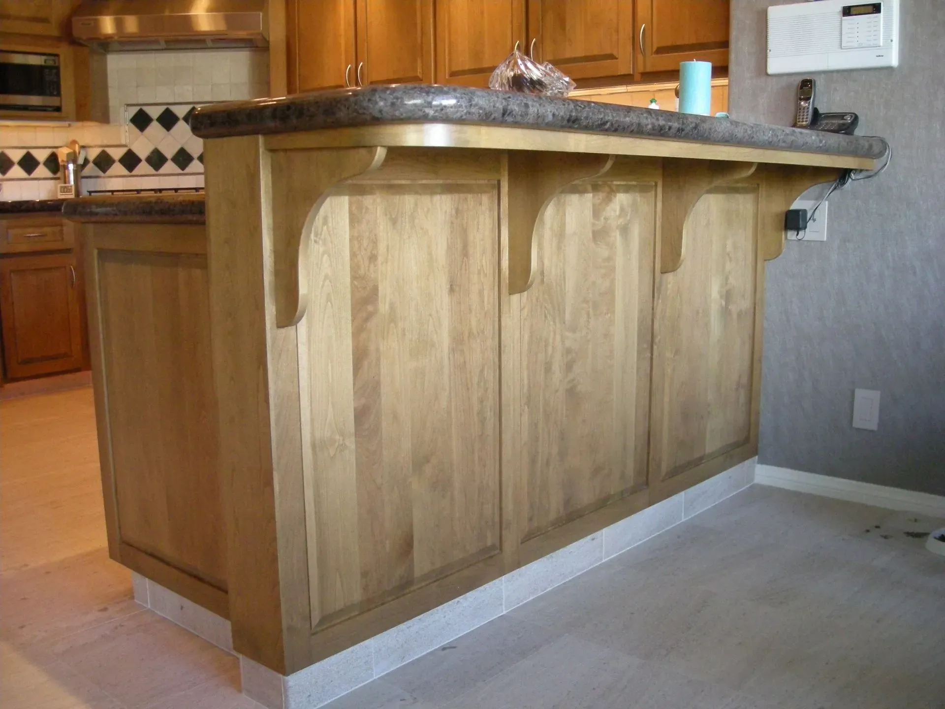 Wooden kitchen island with granite countertop in a tiled kitchen.