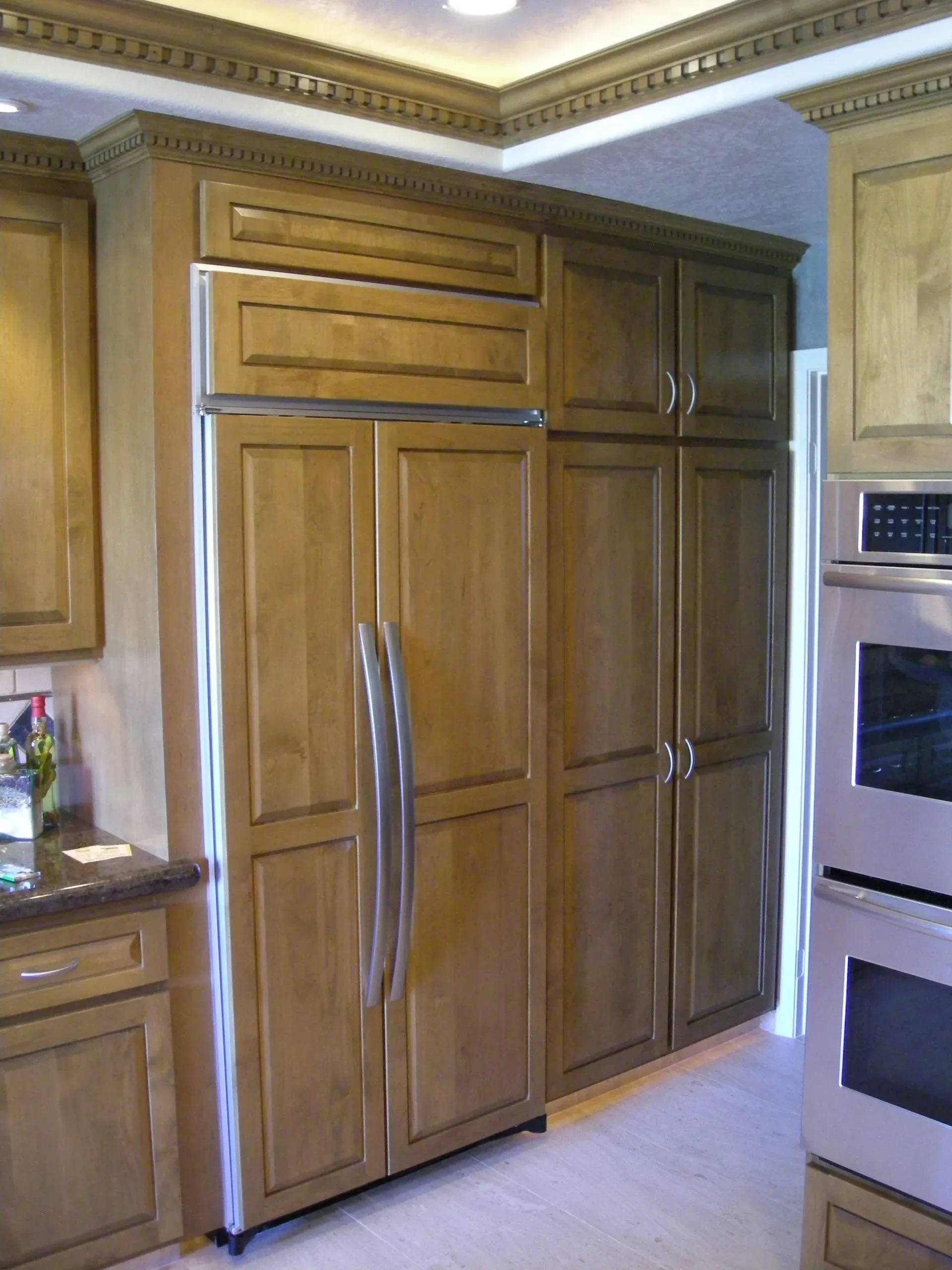 Kitchen with wood cabinets and a built-in stainless steel refrigerator.