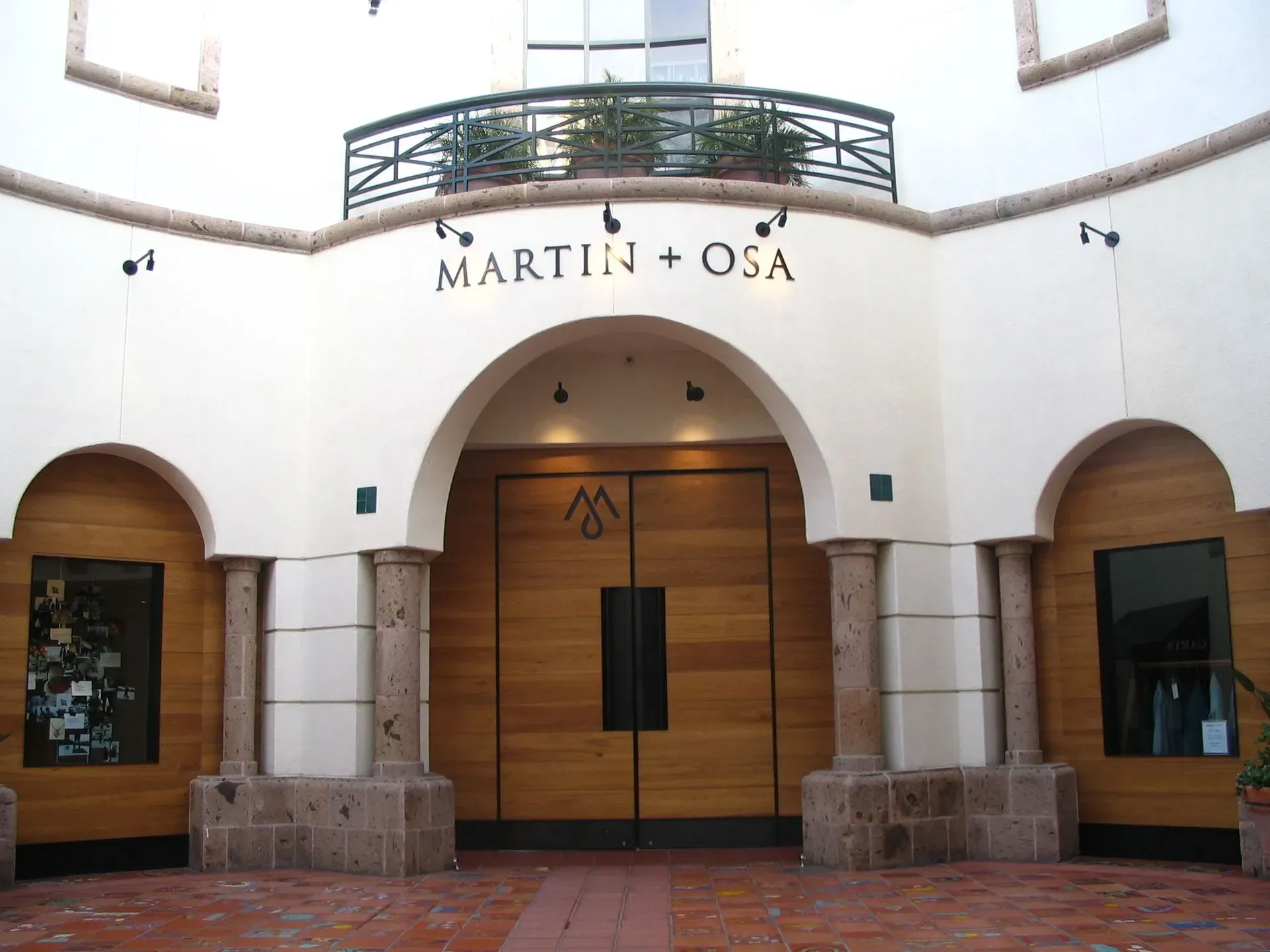 Exterior of Martin + Osa storefront with arched entry, wooden double doors, and display windows