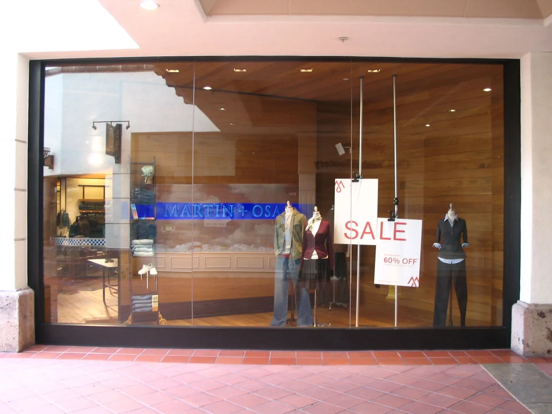 Storefront window with mannequins and a red “SALE” sign displayed inside.