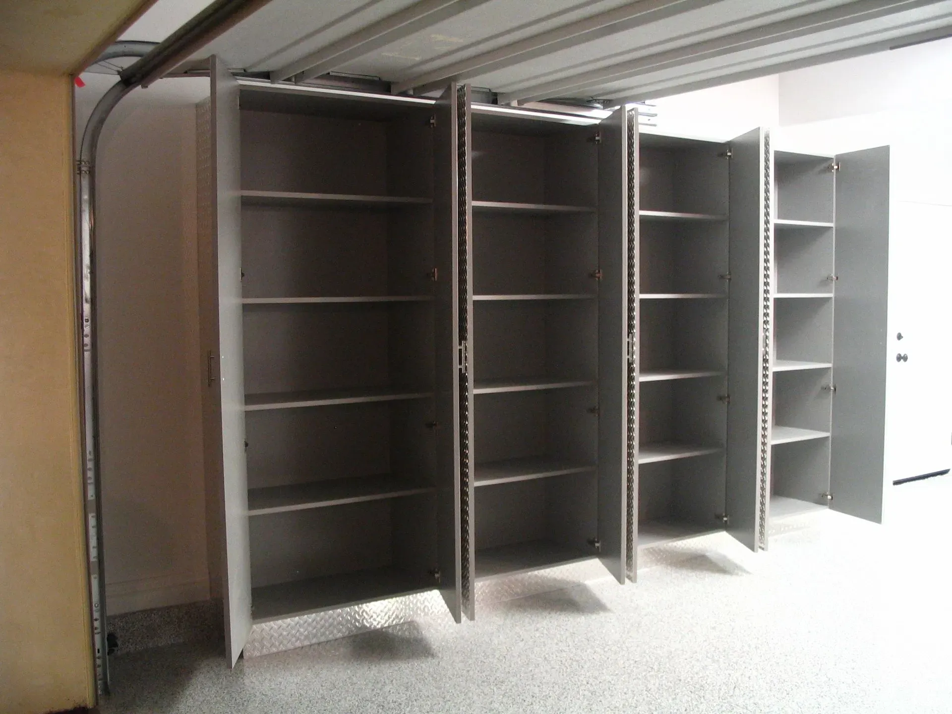 Open gray metal storage cabinets with shelves in a bright room with a concrete floor