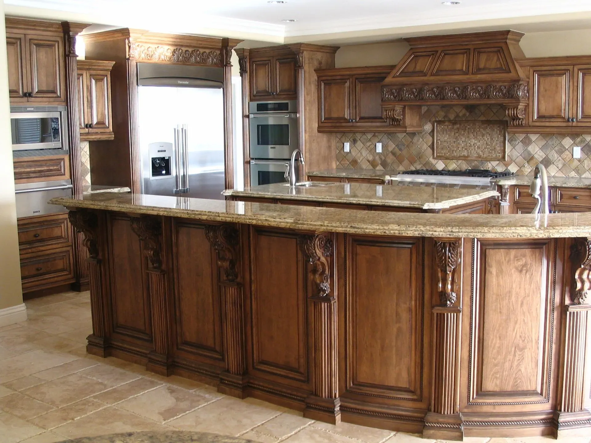 Luxury kitchen with dark wood cabinets, granite island, and stainless steel appliances