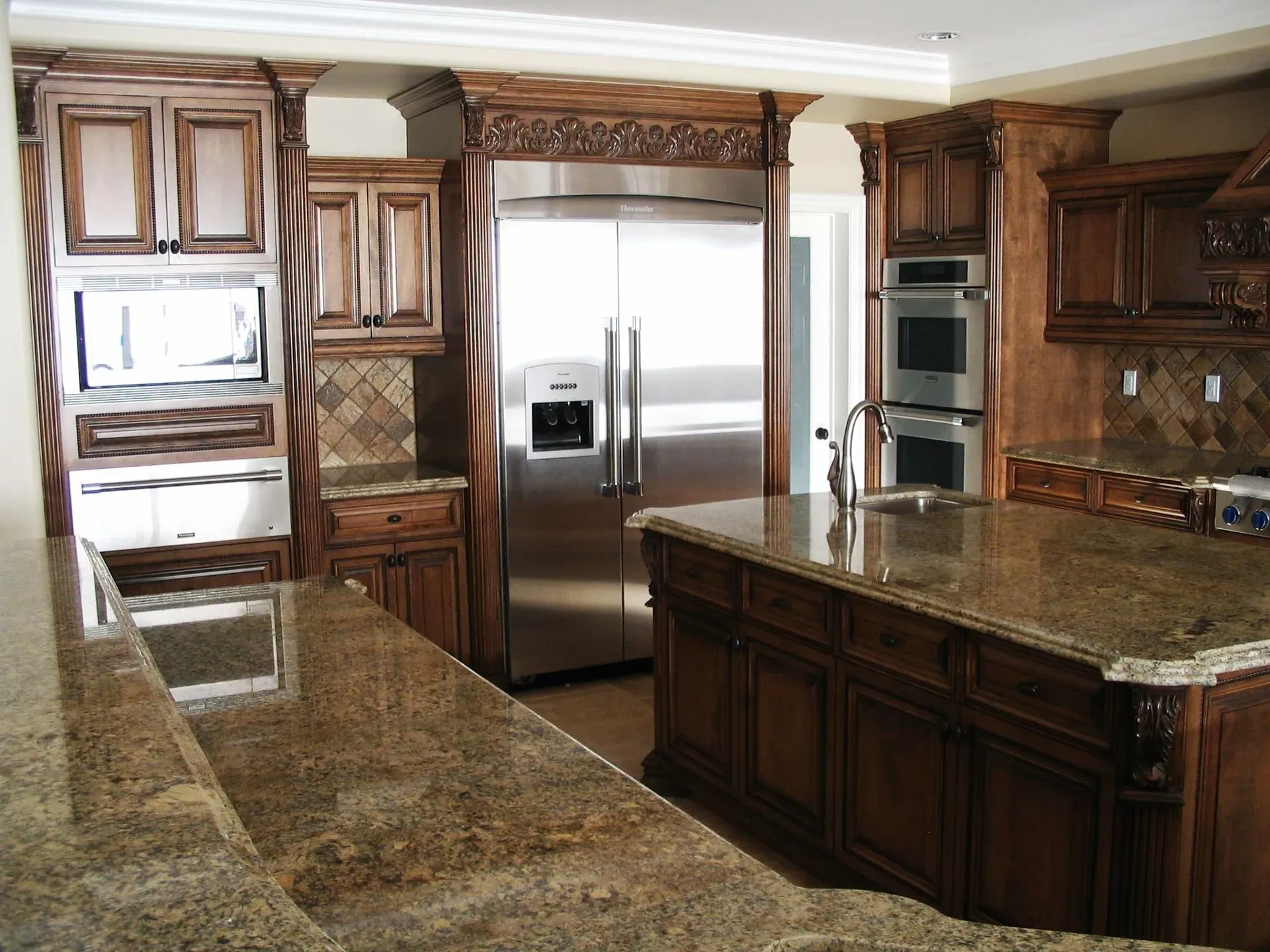 Elegant kitchen with dark wood cabinets, granite countertops, and stainless steel refrigerator.