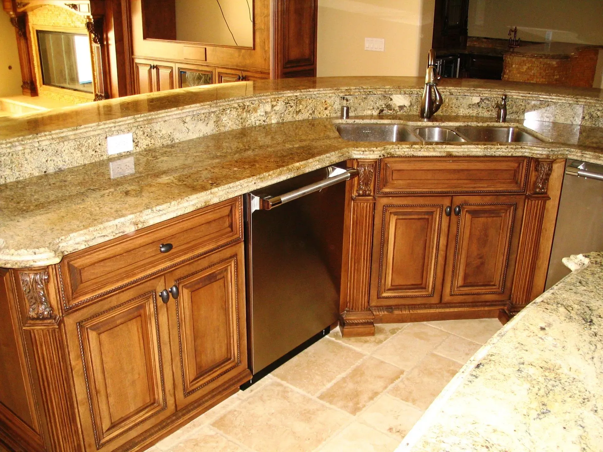 Granite kitchen countertops with wood cabinets and a built-in dishwasher under warm lighting