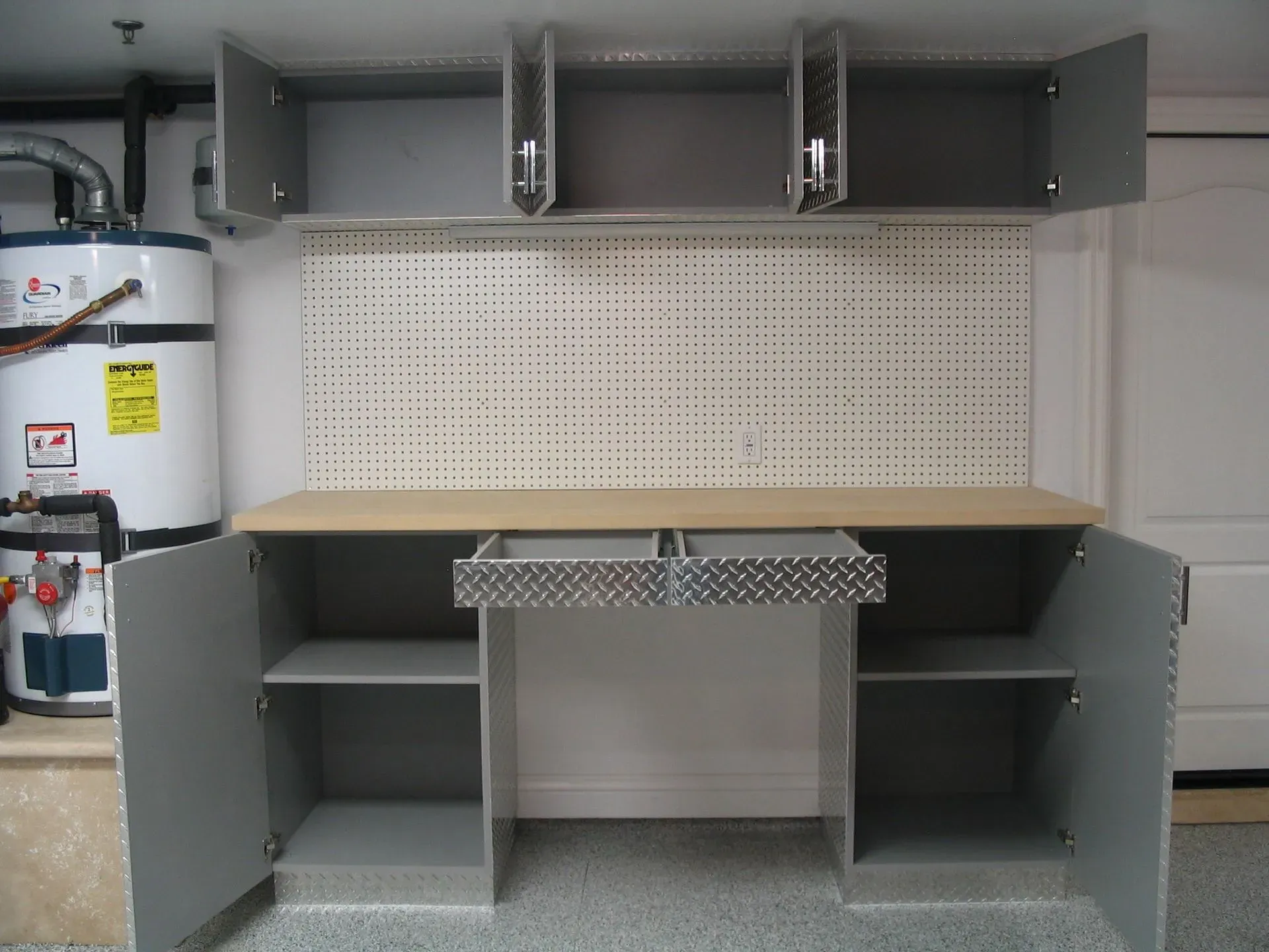 Garage workbench with open cabinets, pegboard, and overhead storage shelves