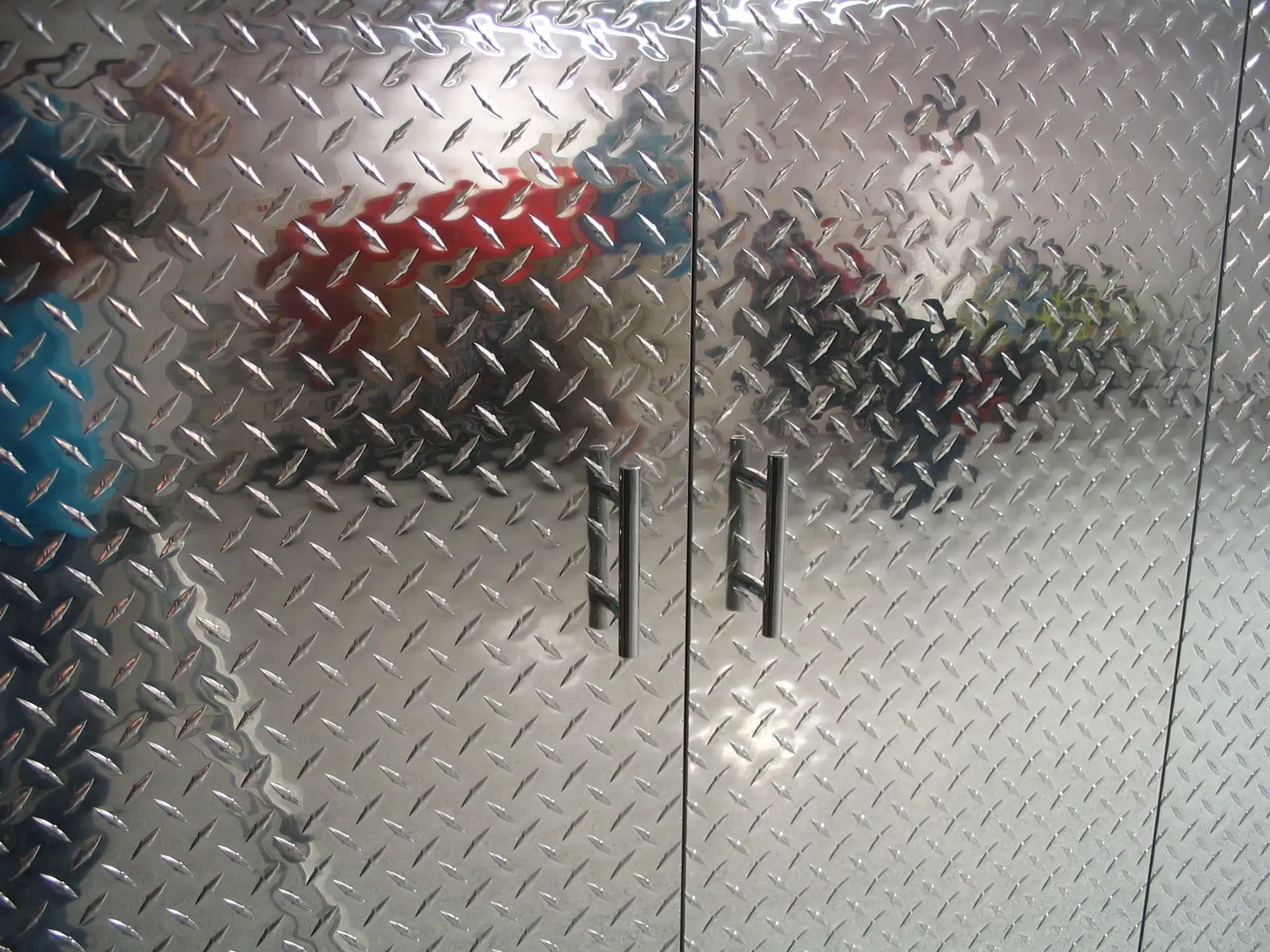 Two people seen through frosted diamond-plate glass doors in a bright indoor space