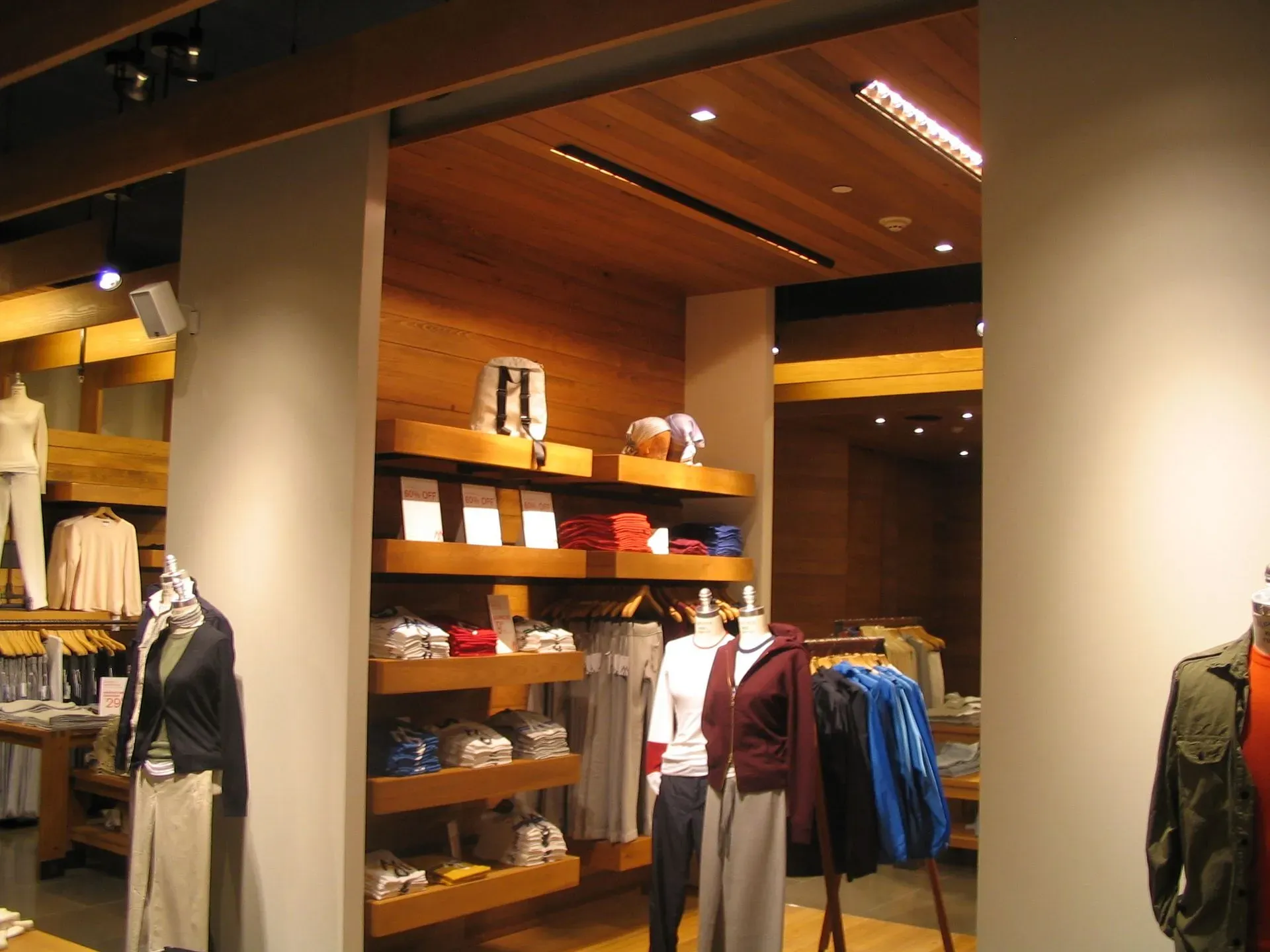 Clothing store interior with shelves of folded clothes and mannequins in jackets and sweaters