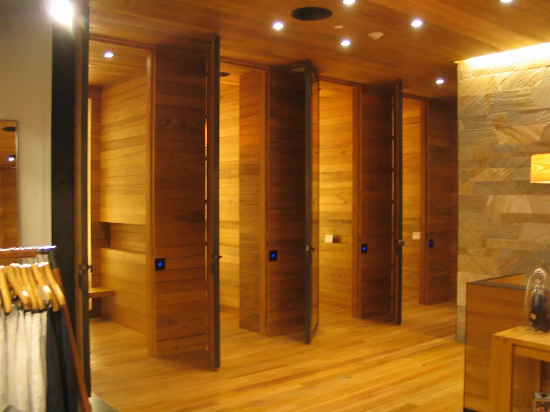 Wood-paneled changing room with multiple private wooden stalls and warm recessed lighting