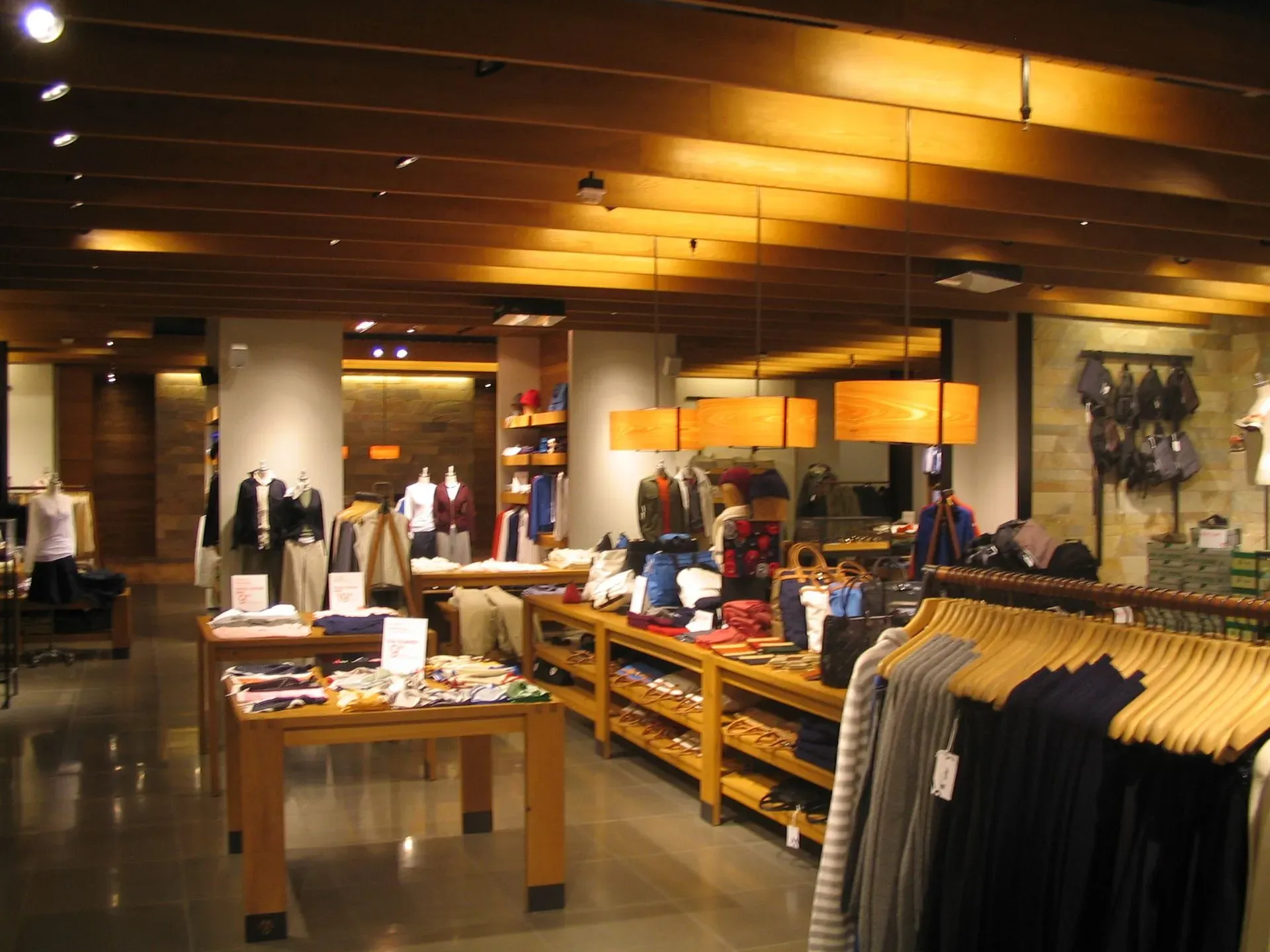 Clothing store interior with racks of folded shirts and hanging garments under warm ceiling lights