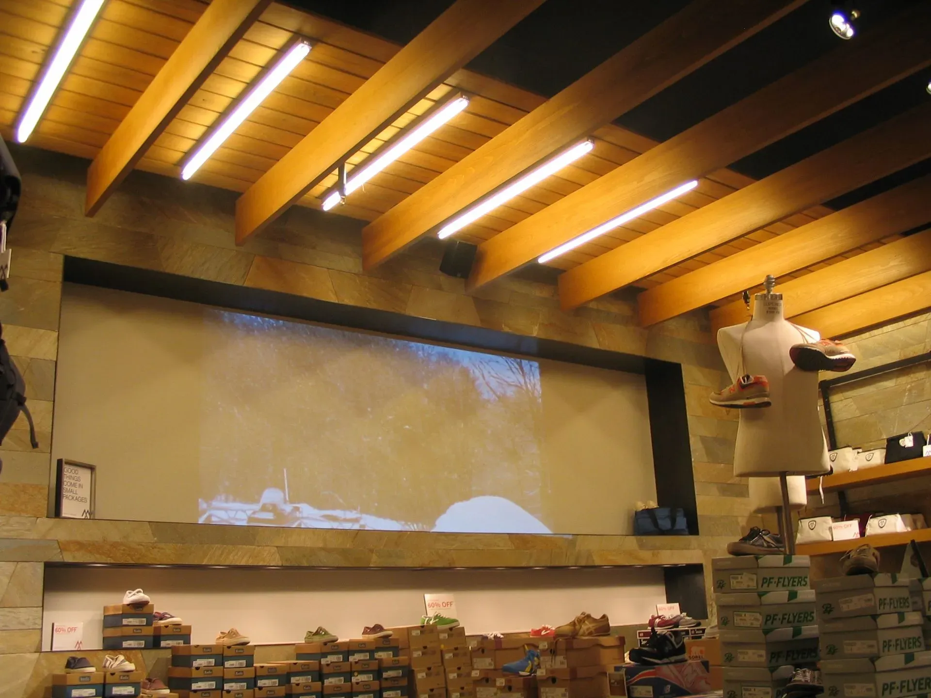 Indoor warehouse with stacked boxes, wooden beams, and a large blank projection screen