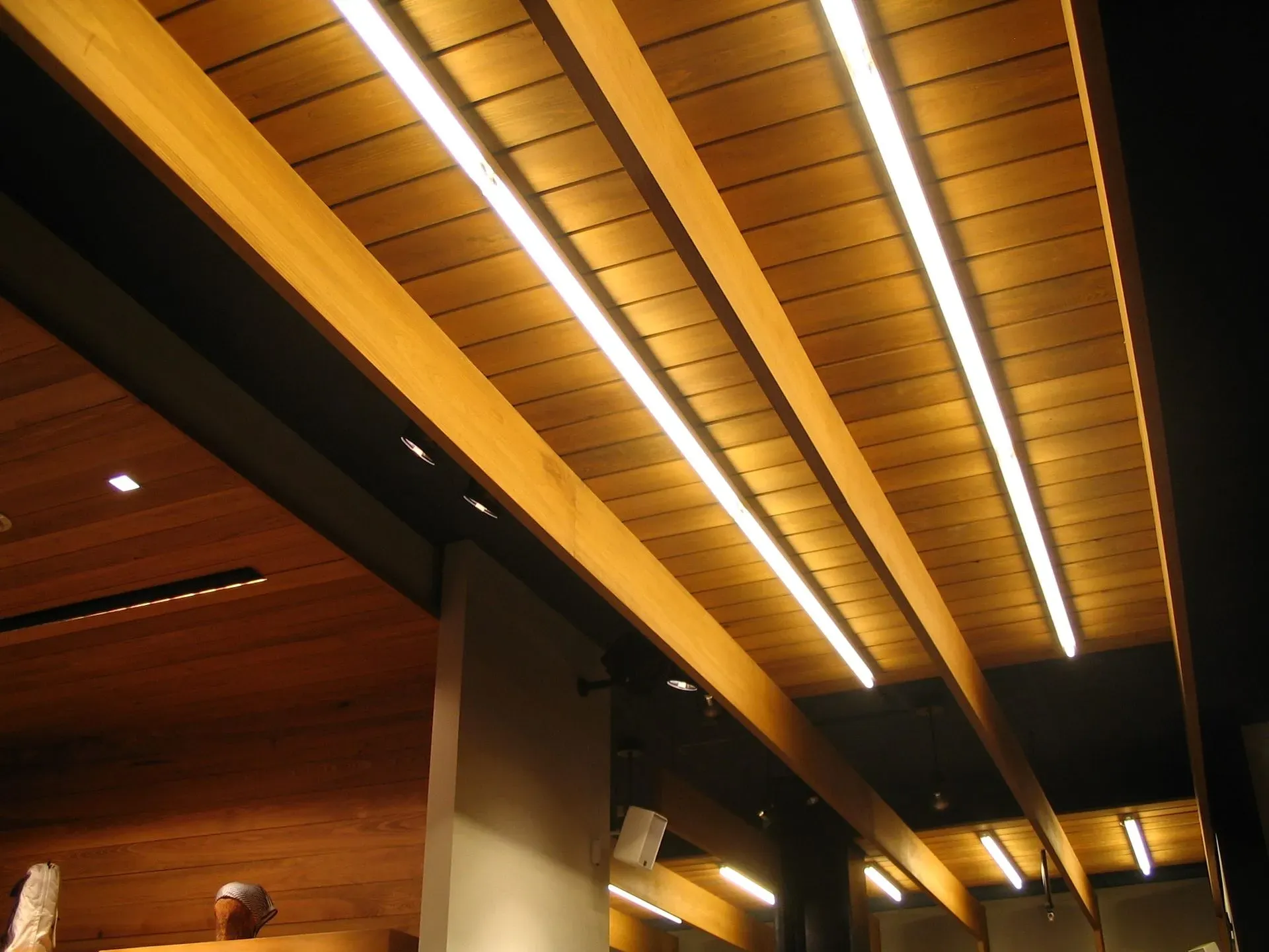 Wood-paneled ceiling with warm recessed strip lighting in a modern indoor space