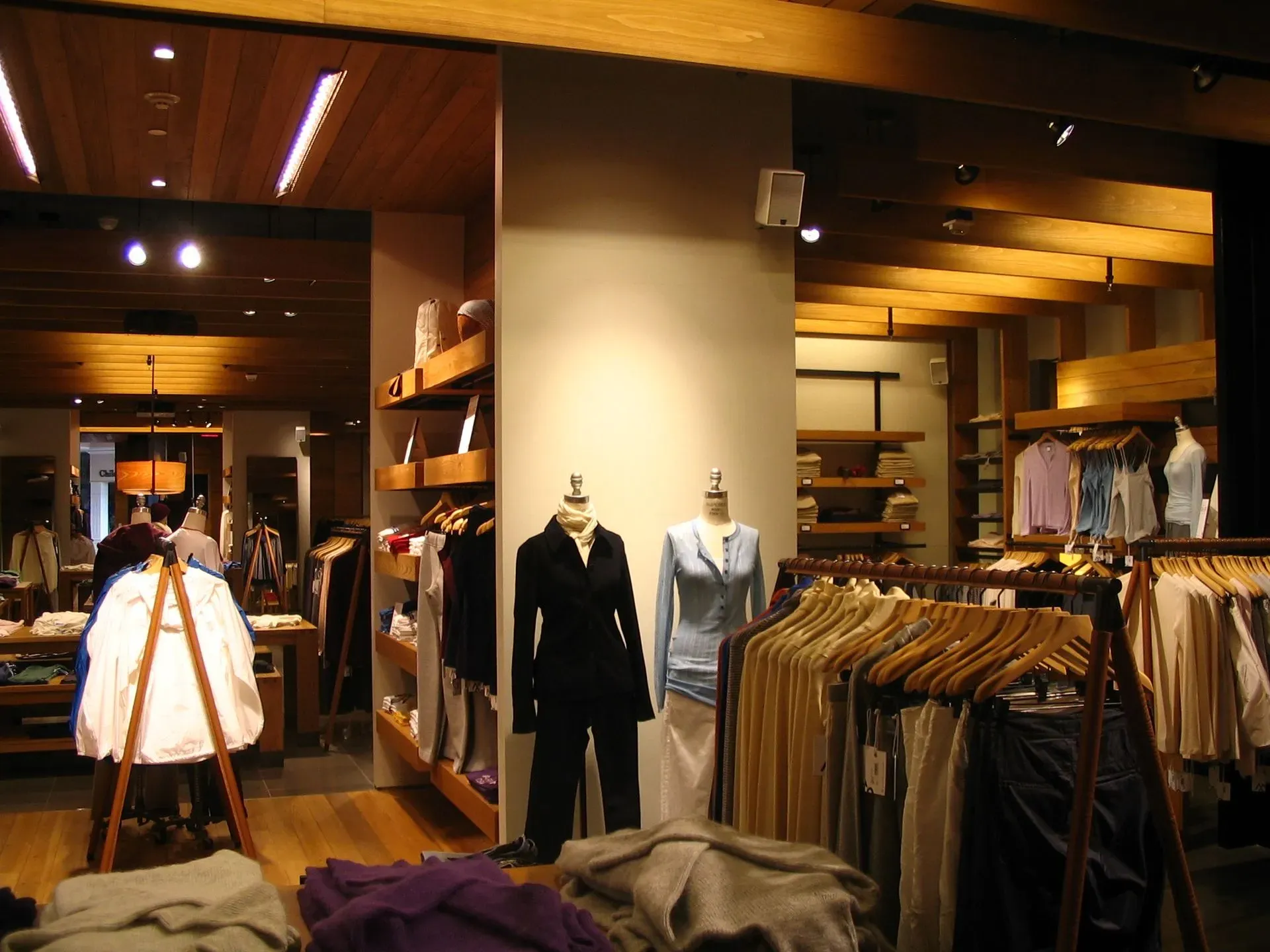 Clothing boutique interior with racks of suits and shirts under warm wood lighting