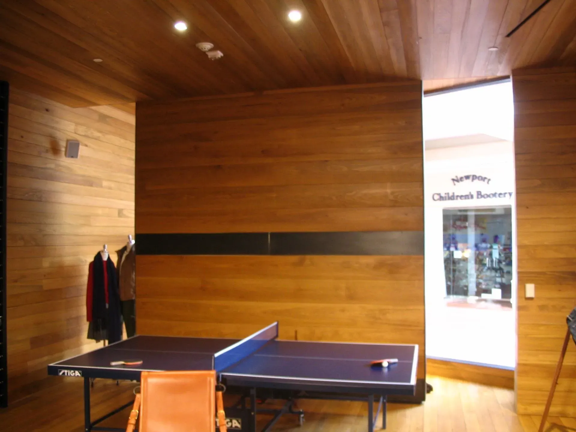 Indoor ping-pong table in a wood-paneled room with a bright doorway