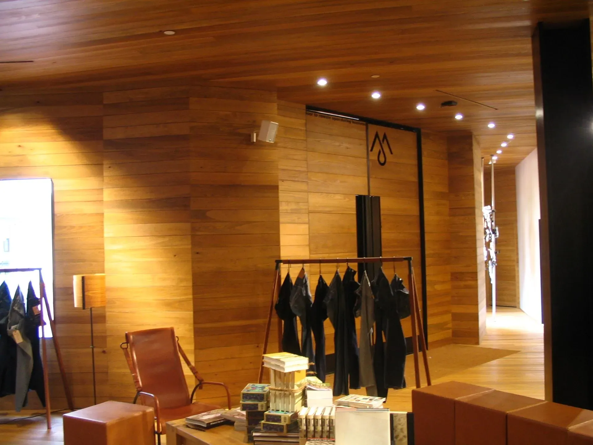Wood-paneled boutique with clothing racks, warm lights, and a chair in the foreground