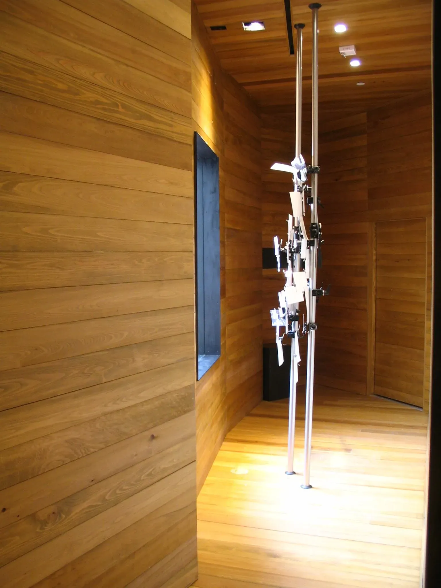 Wood-paneled hallway with a tall metallic sculpture under ceiling lights
