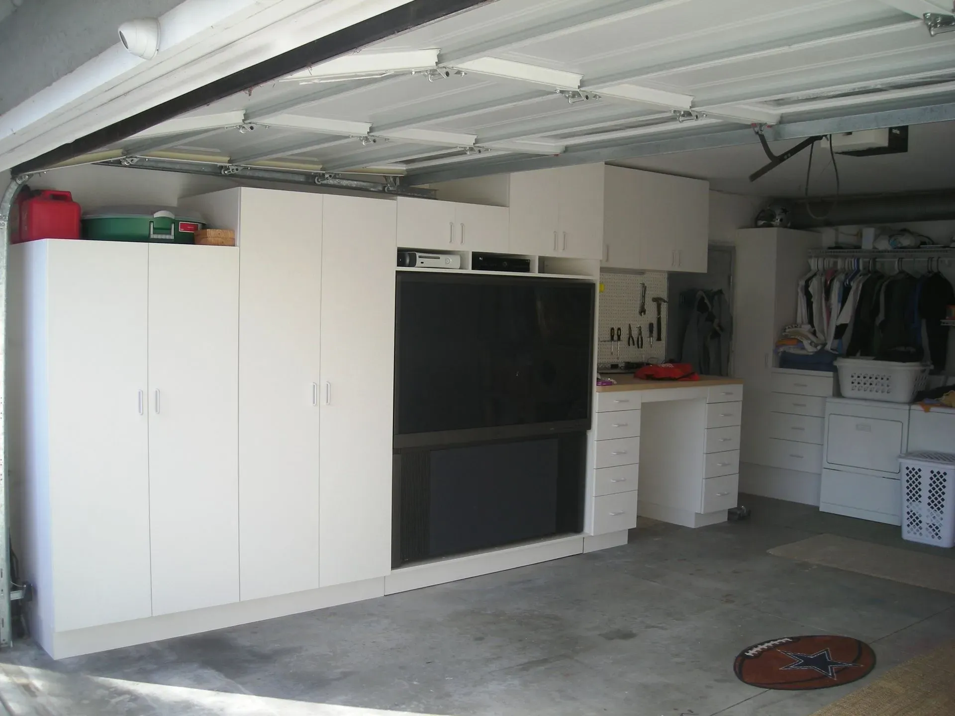 Garage interior with white cabinets, a black appliance, and storage bins along the wall