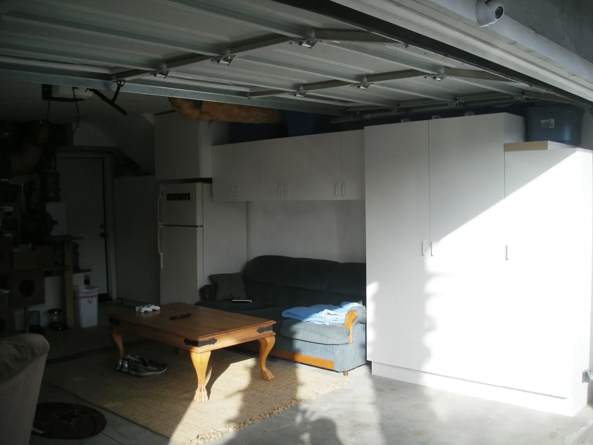 Garage interior with a couch, coffee table, and shelves in bright sunlight