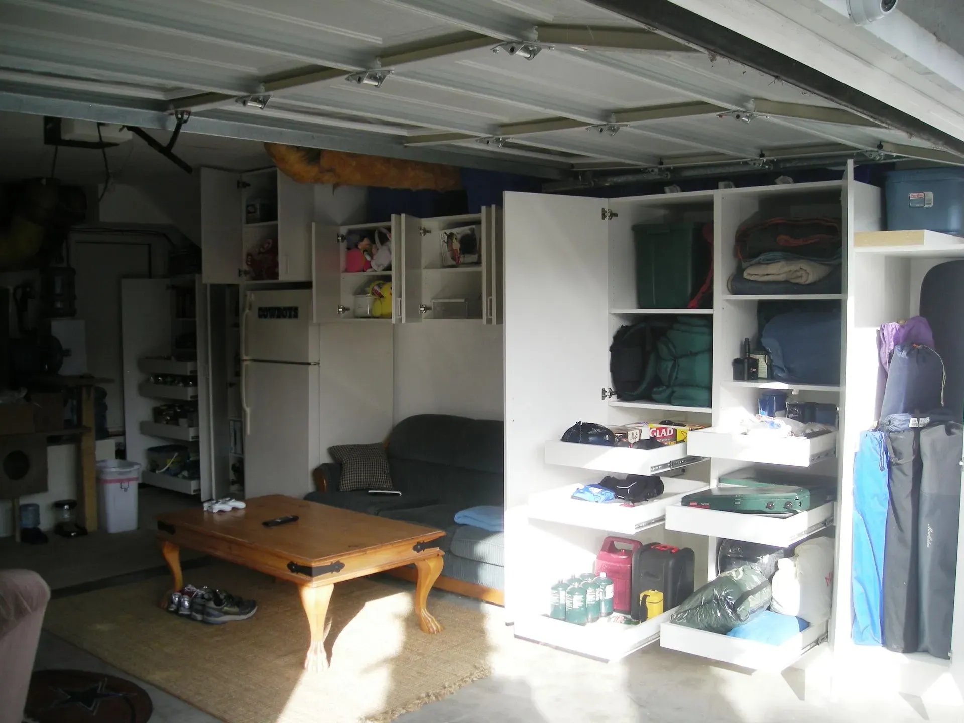 Garage interior with a wooden coffee table, shelving, storage bins, and a bicycle in the foreground.