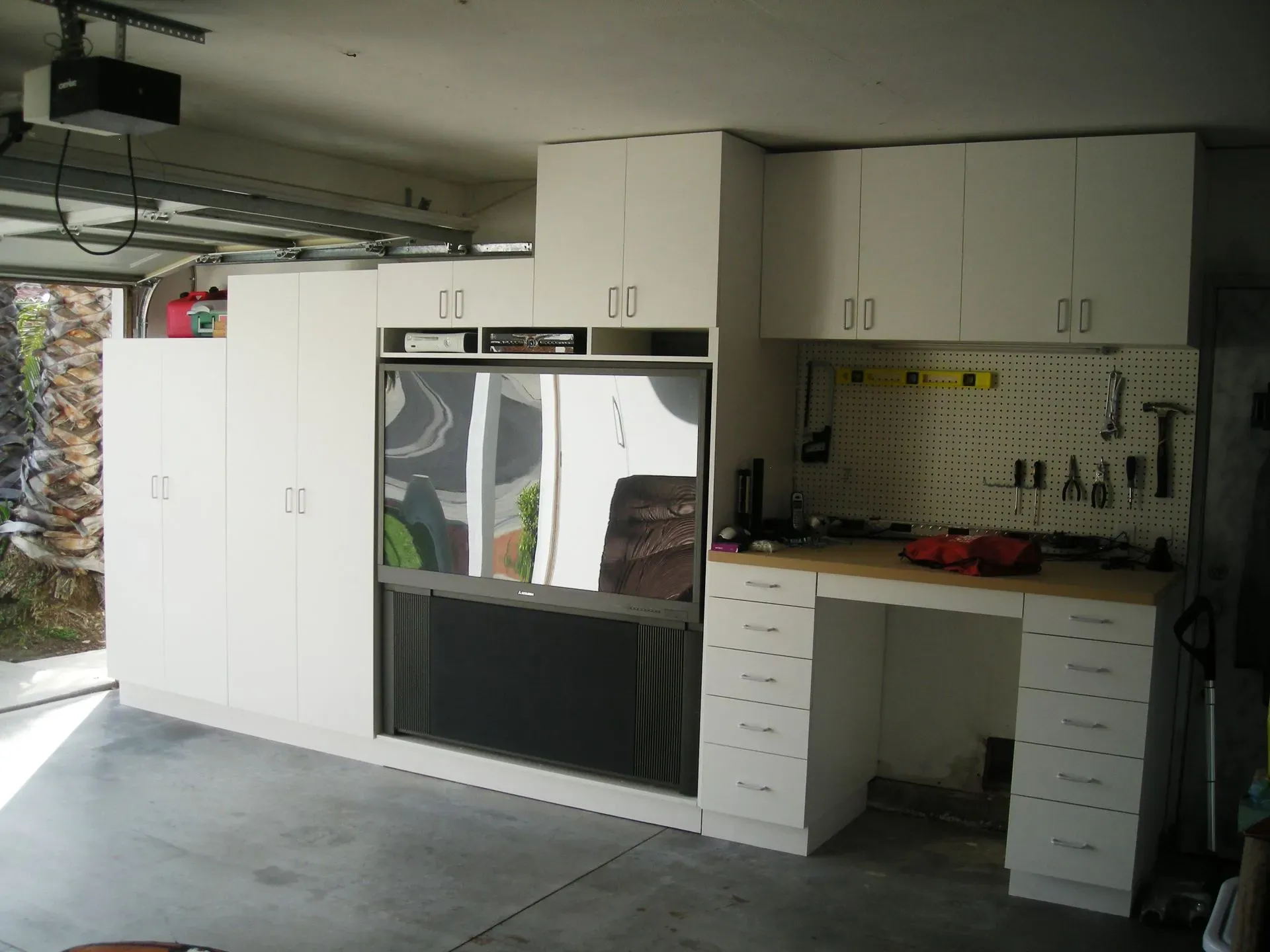 Garage with white cabinets, built-in oven, workbench, and concrete floor