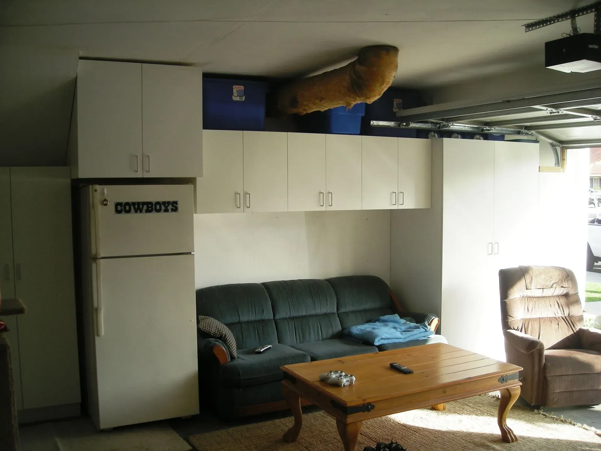 Basement living room with couch, recliner, coffee table, refrigerator, and cabinets