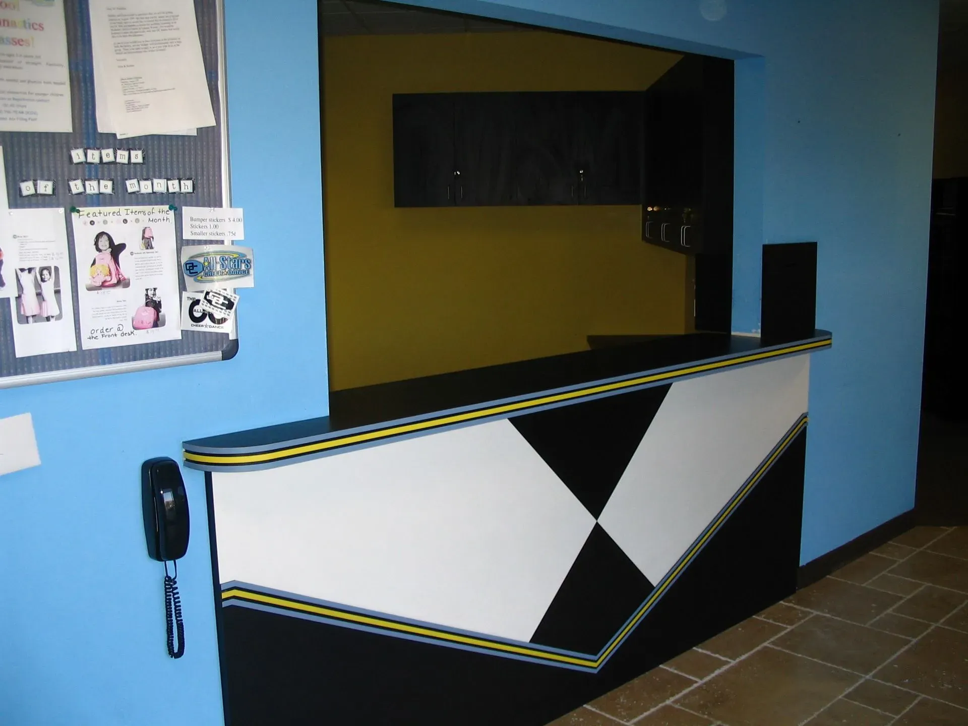 Empty reception desk with black, white, and yellow geometric paneling in a blue-walled lobby