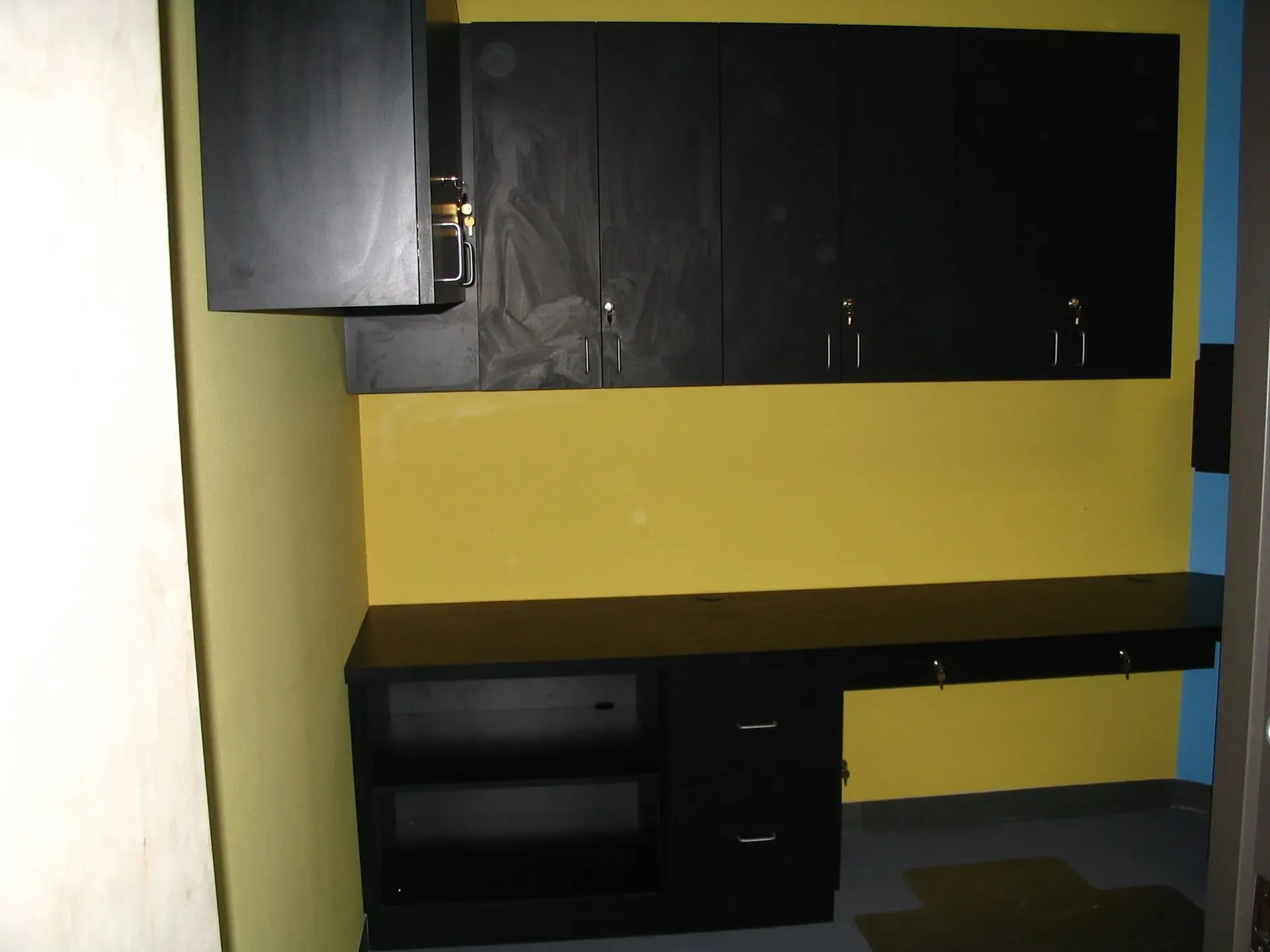 Small kitchen area with yellow walls, black cabinets, and a dark countertop.