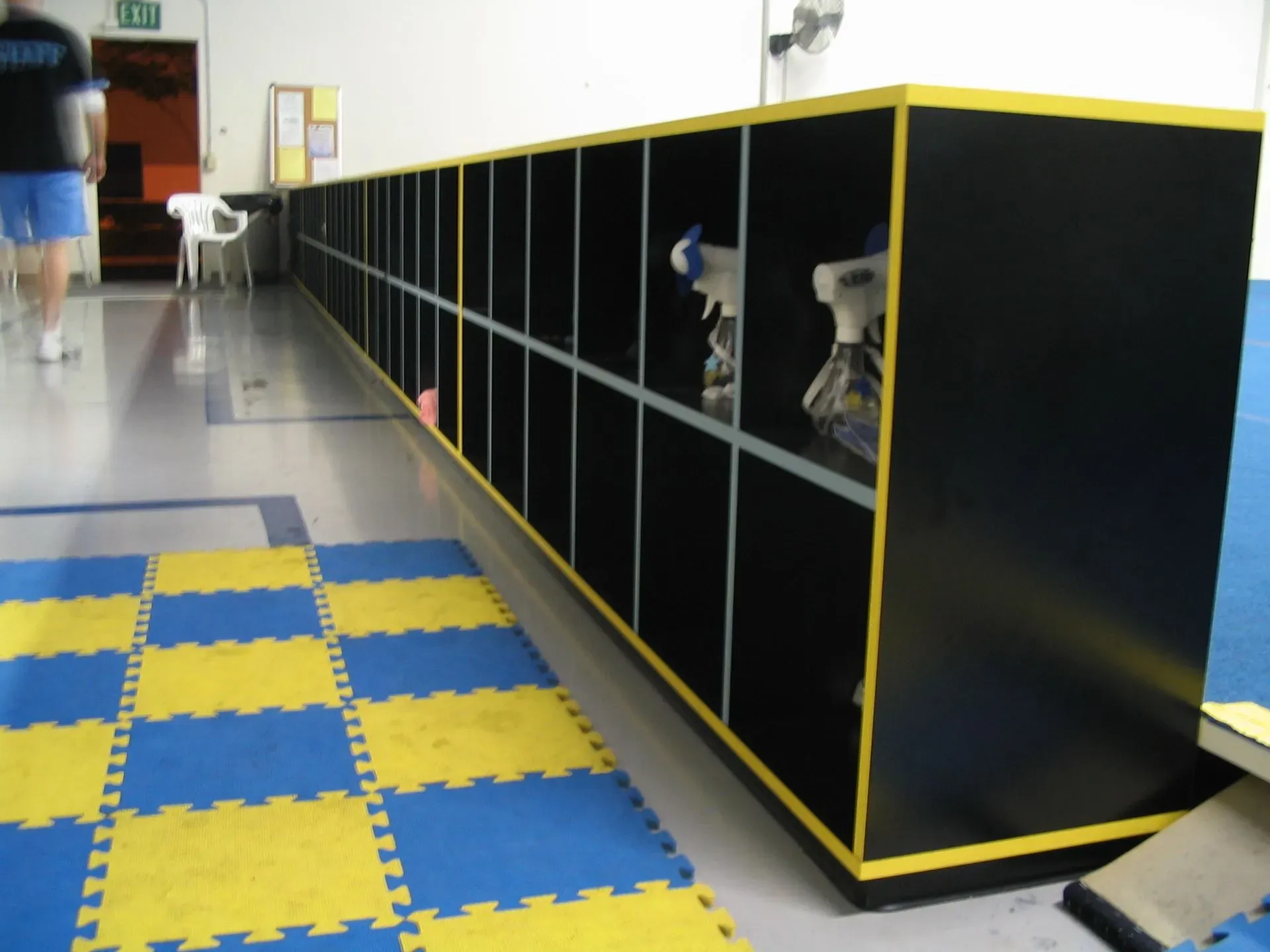 Black-and-yellow cubby bench in a gym with blue-and-yellow foam floor tiles