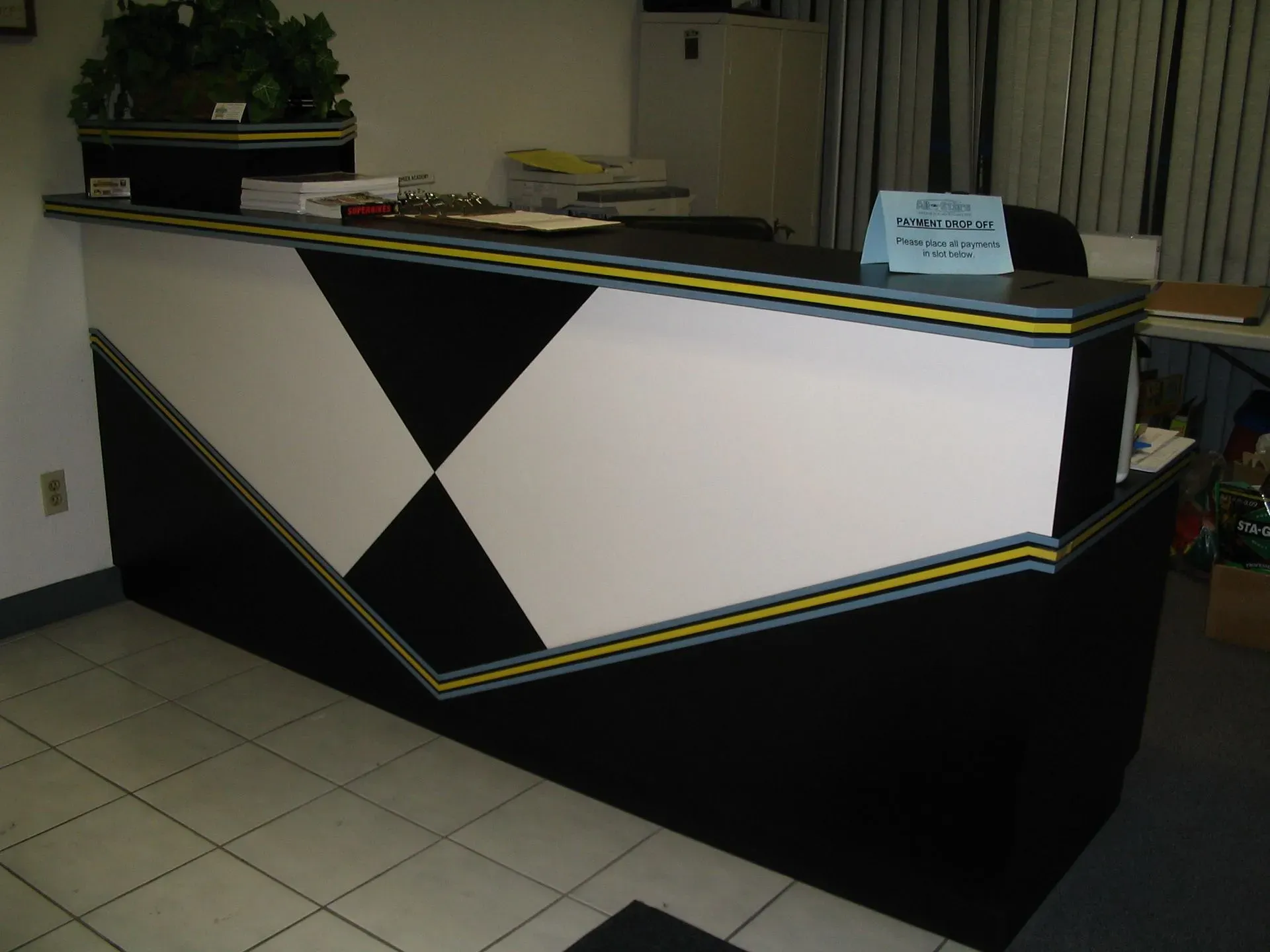 Modern black reception desk with white geometric panels in a tiled lobby