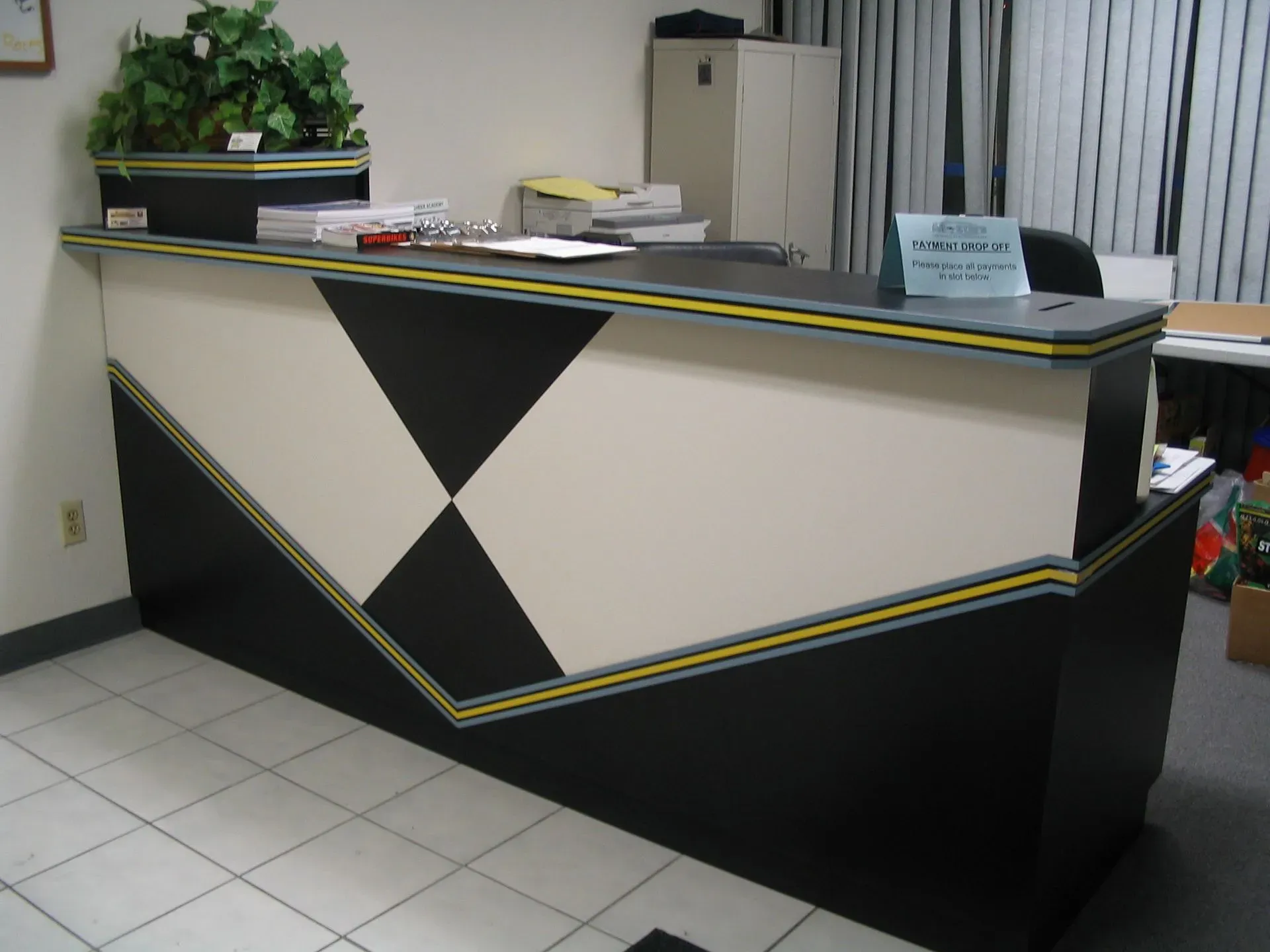 Front desk reception counter with black, white, and yellow geometric design in an office lobby.