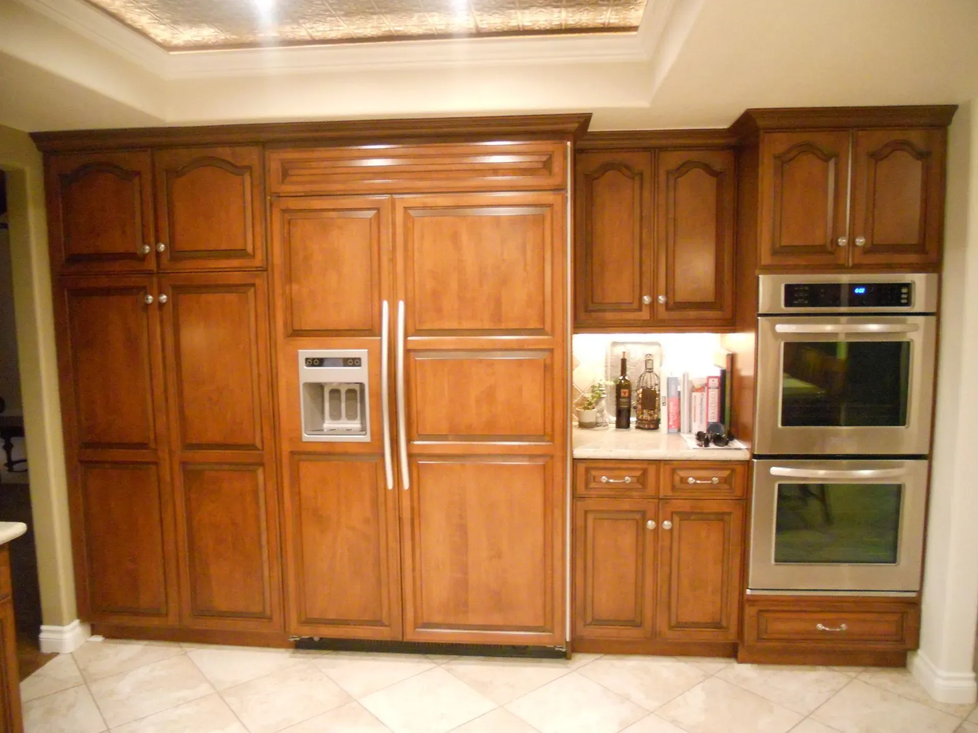 Wood-paneled kitchen wall with built-in refrigerator, oven, and cabinets