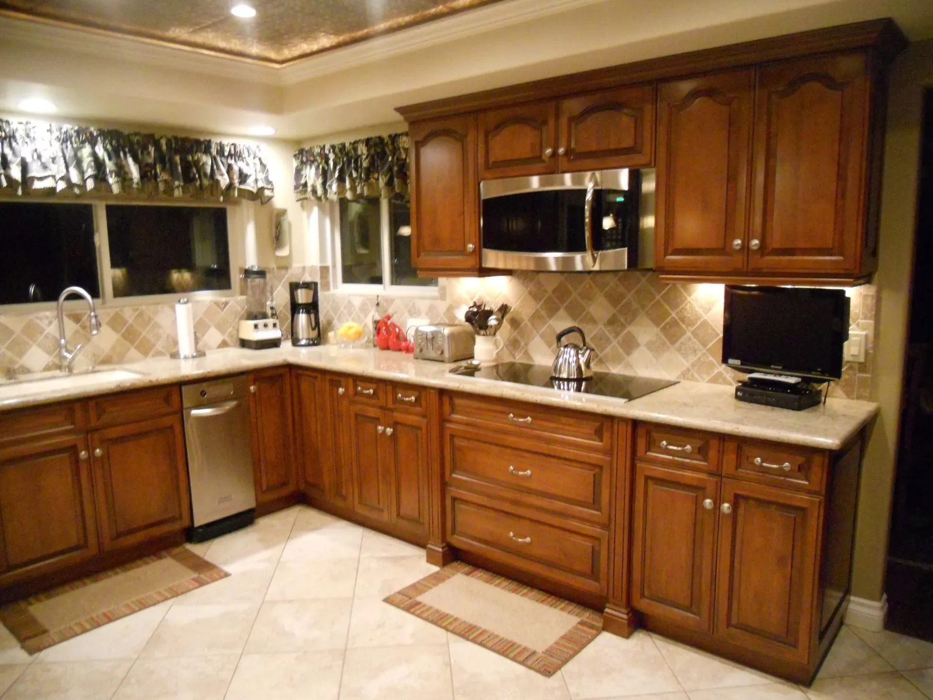 Spacious kitchen with dark wood cabinets, beige countertops, stainless appliances, and tiled floor