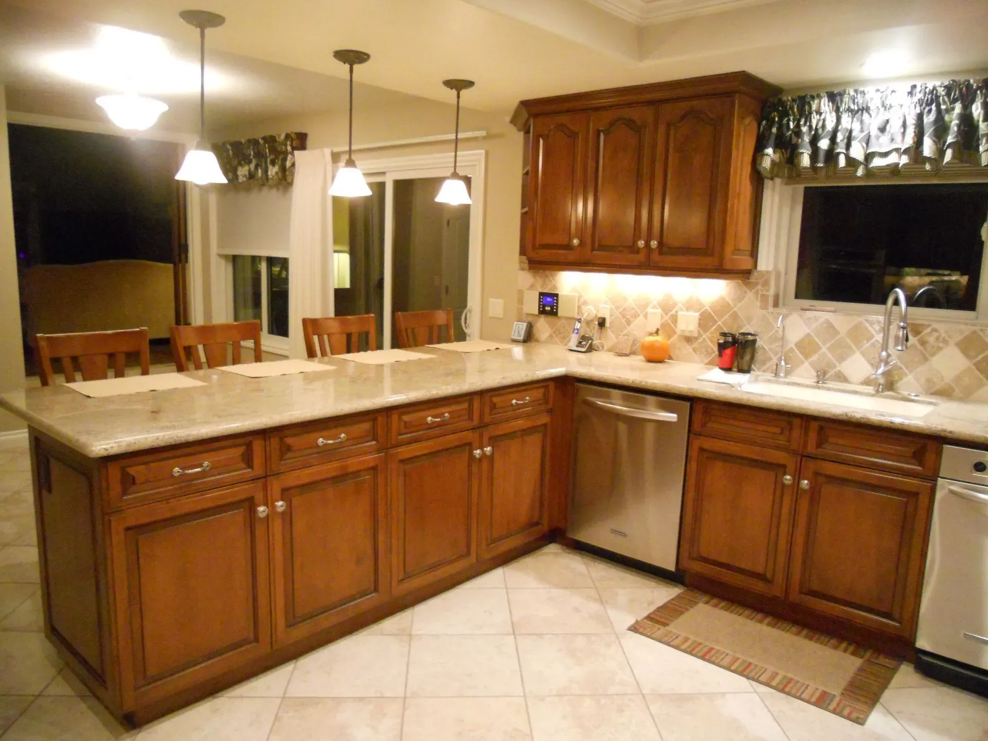 Spacious kitchen with wooden cabinets, beige countertops, tile floor, and pendant lights