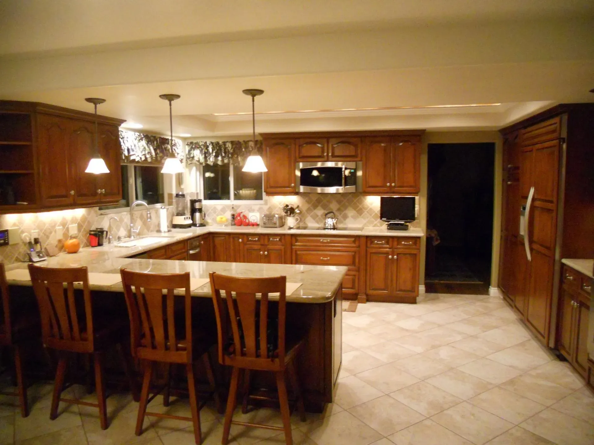 Spacious kitchen with wooden cabinets, island seating, granite counters, and tiled floor