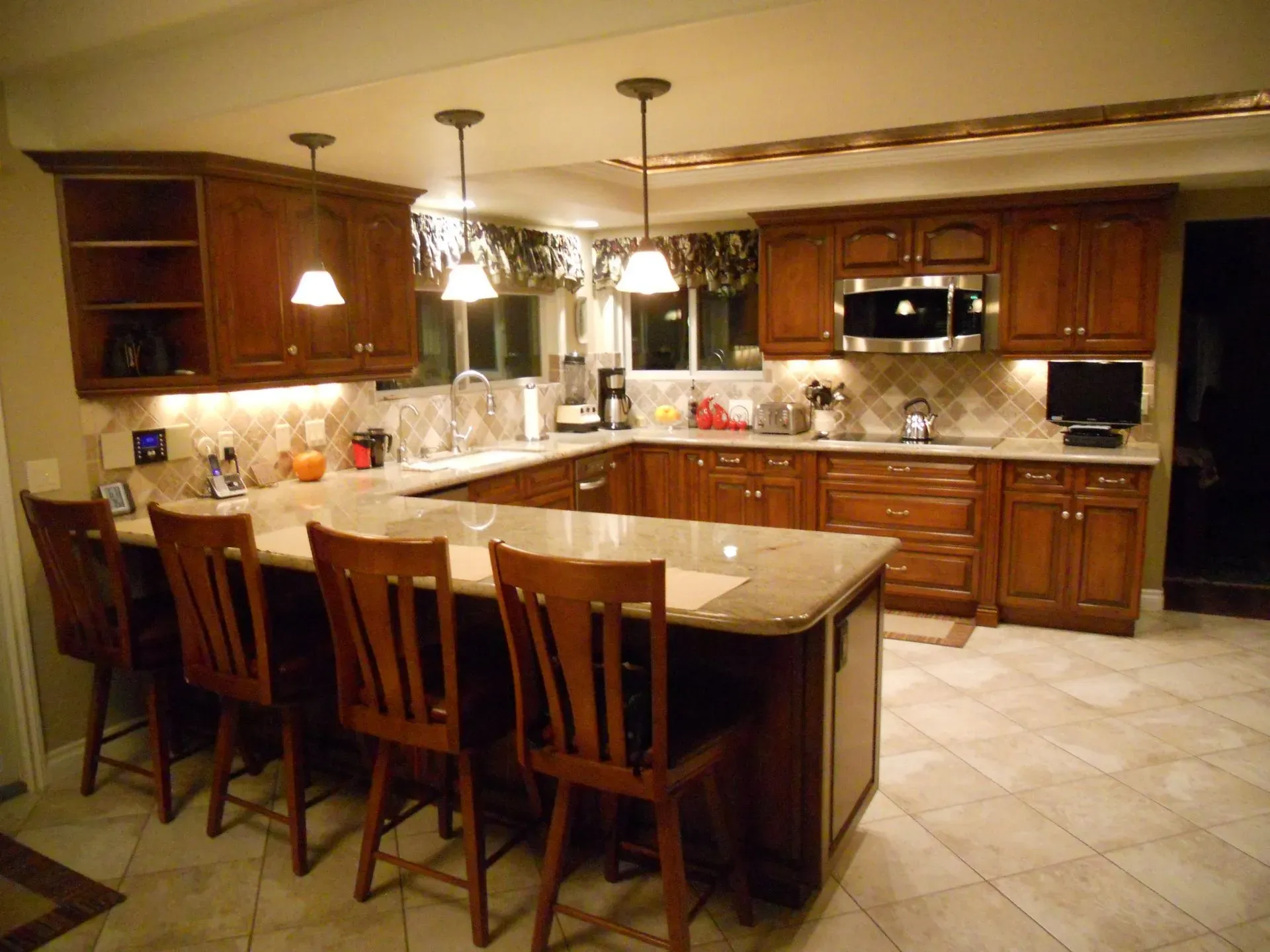 Spacious kitchen with wood cabinets, granite island, bar stools, and pendant lighting