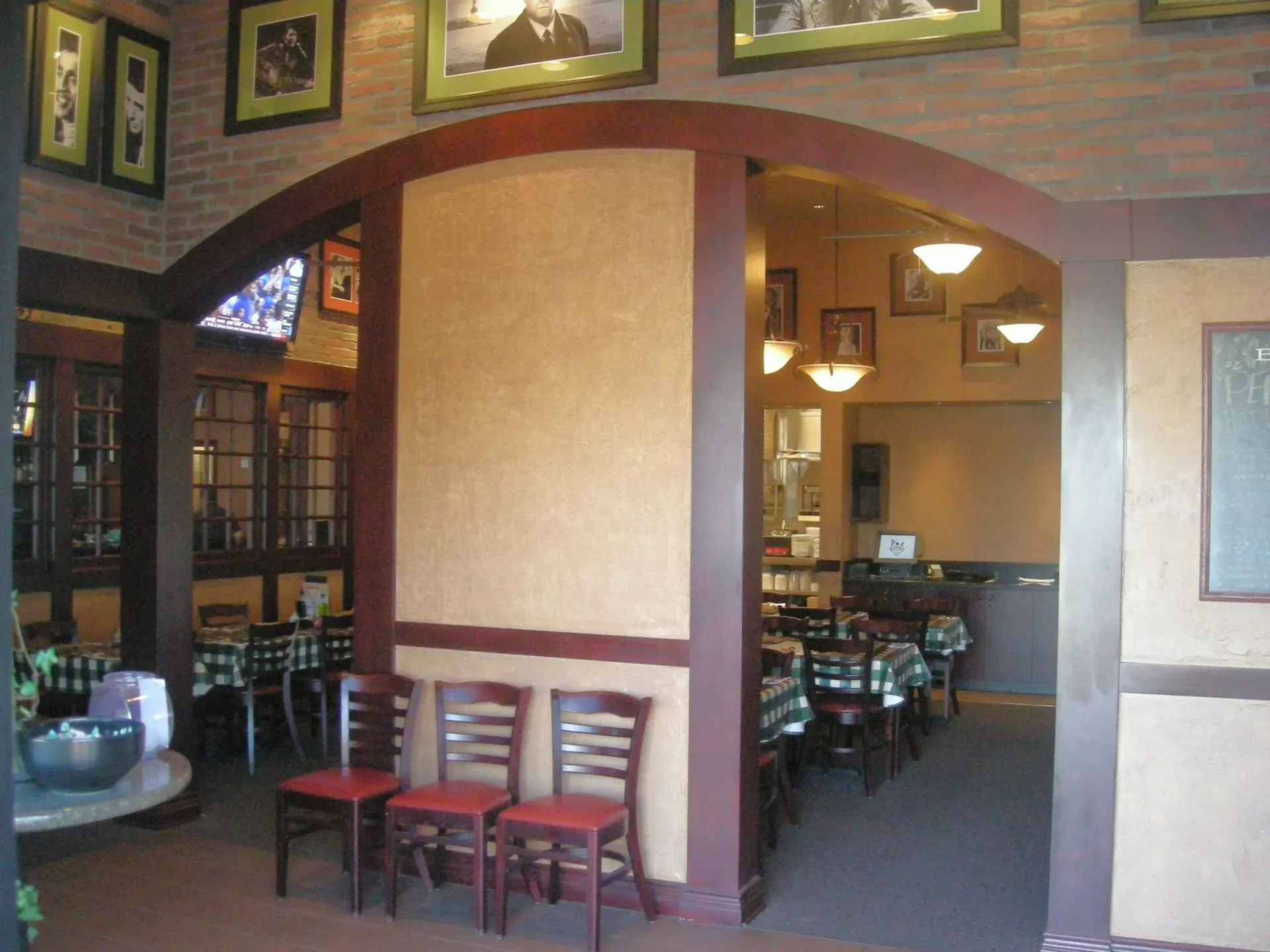 Empty restaurant interior with arched doorway, wooden chairs, and warm hanging lights