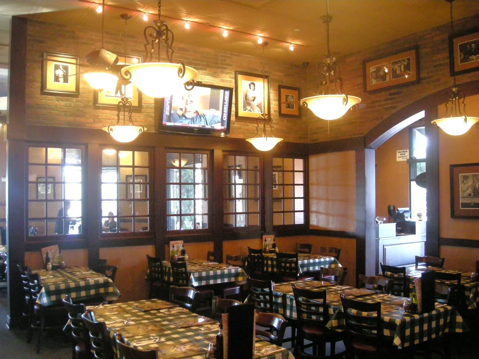 Cozy restaurant dining room with wooden tables, hanging lights, and framed wall art
