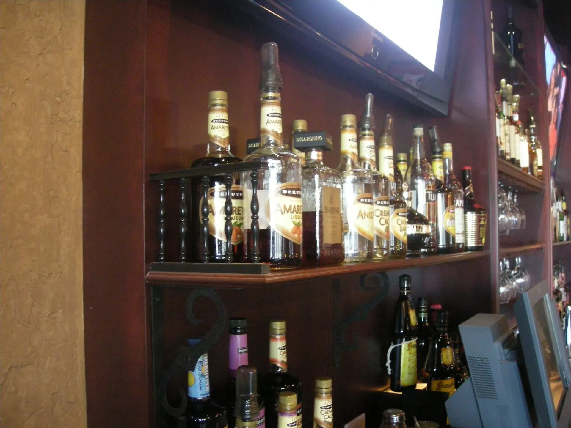Wooden bar shelves lined with assorted liquor bottles and glassware in a dim interior.